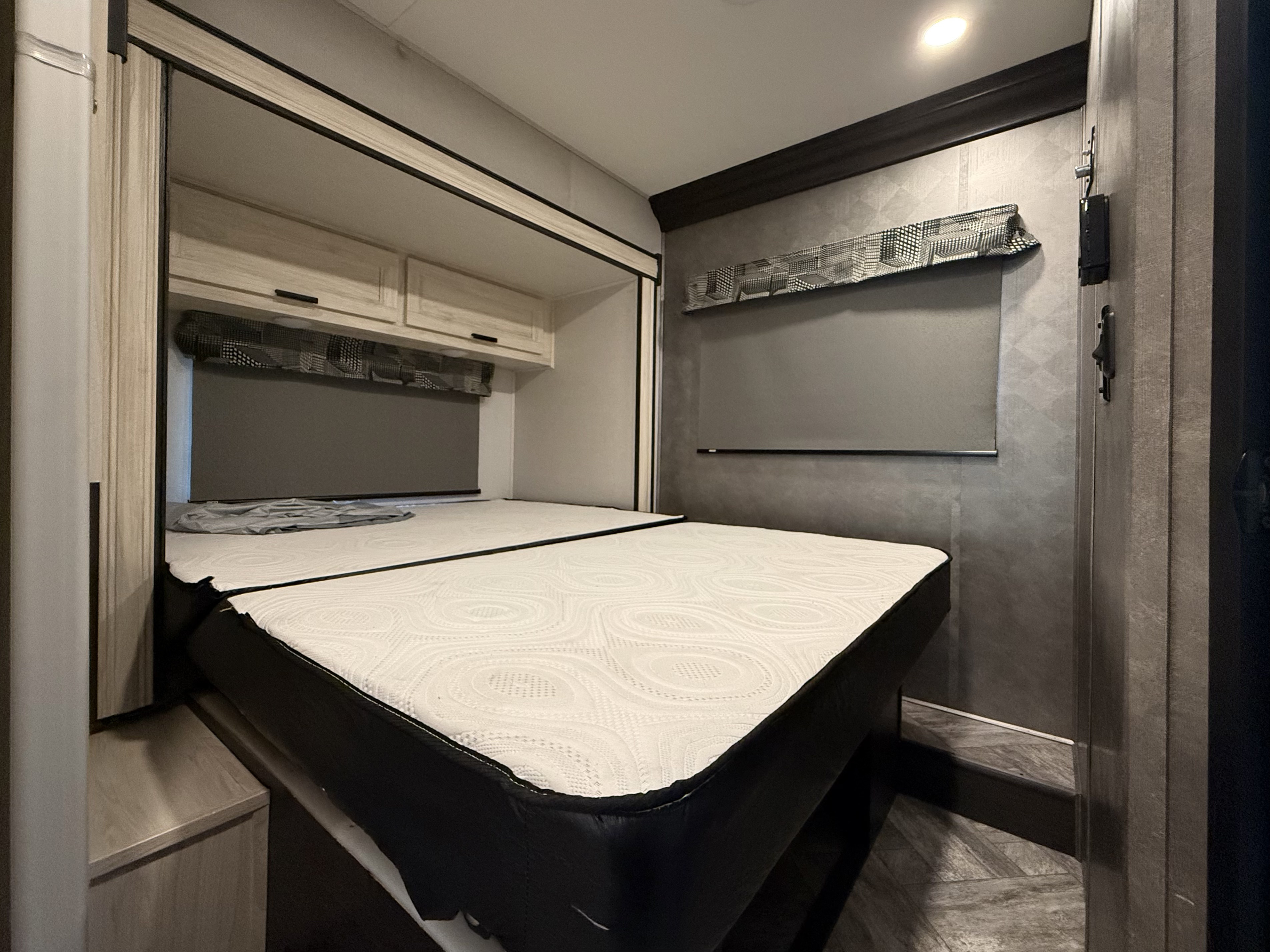 Modern RV rental bedroom featuring a clean white mattress, sleek overhead storage, and a stylish window blind.. Forest River Sunseeker LE 2022