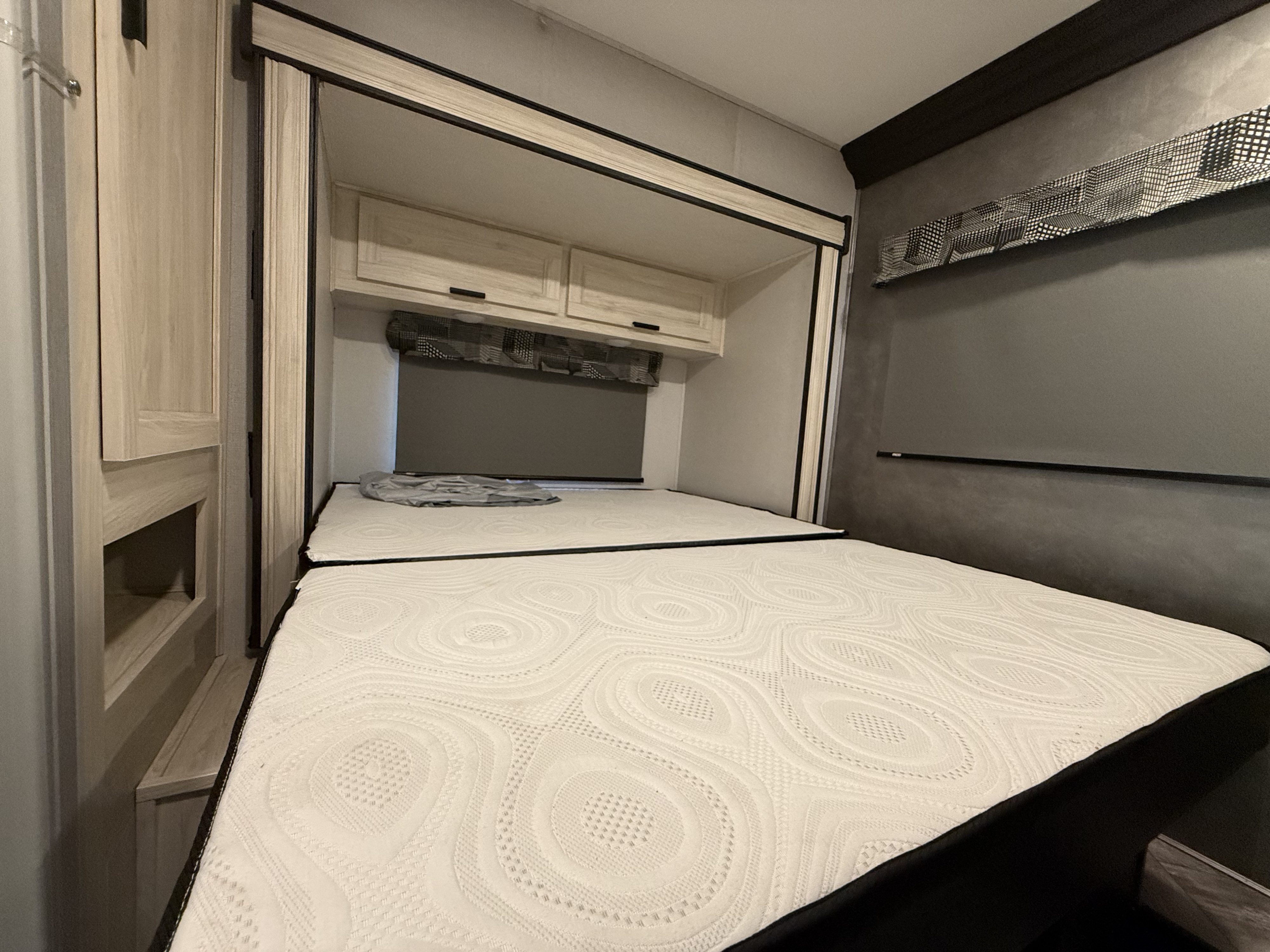 RV rental bedroom with a comfy, split mattress, overhead storage, and window with a dark privacy shade. Ideal for travel.. Forest River Sunseeker LE 2022