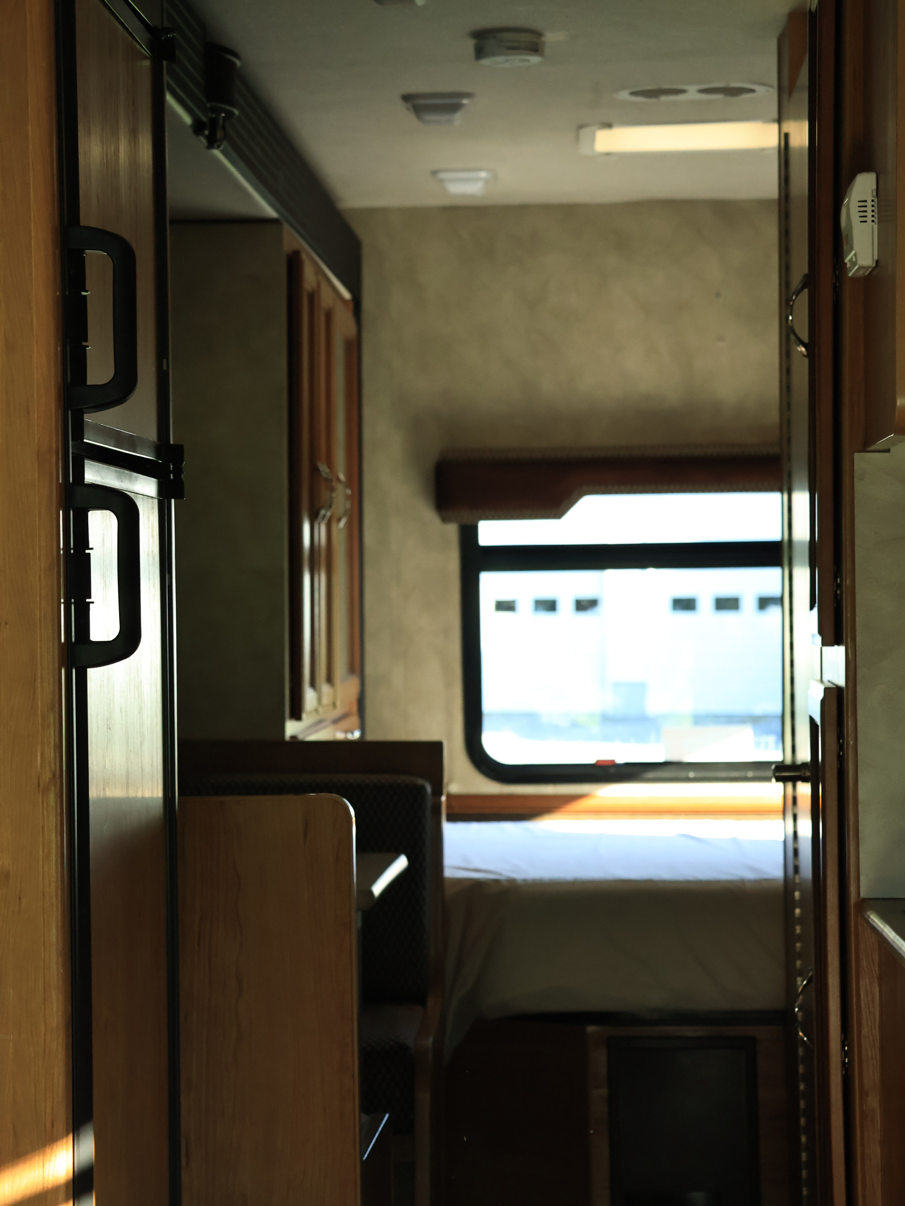 Inside an RV rental, showcasing the kitchen area, dinette seating, and bedroom beyond. Natural light fills the cozy interior.. Jamboree Sport 2015