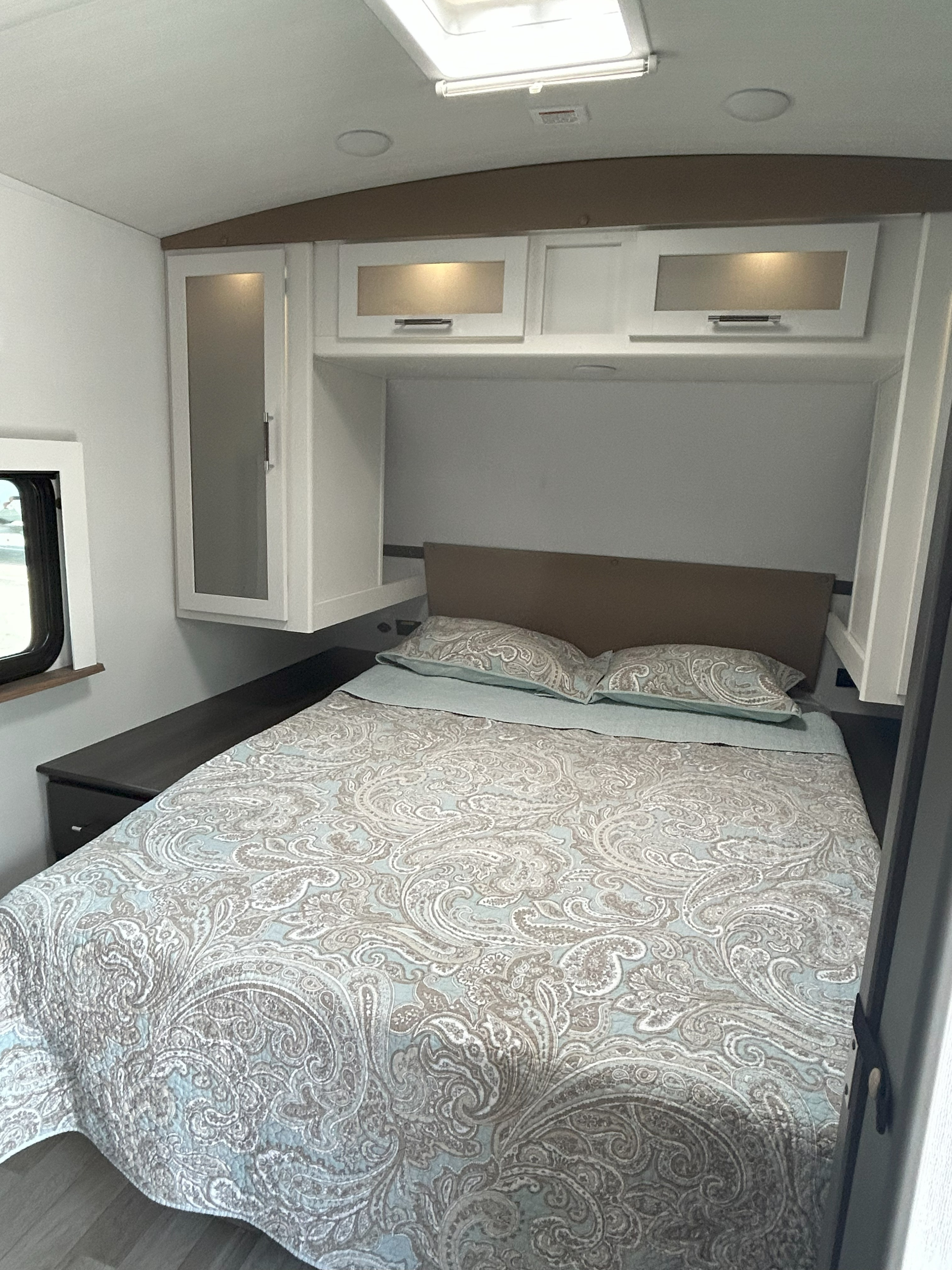 Modern RV rental bedroom with white cabinets, light blue and brown patterned bedding, and a simple headboard.. Keystone RV Bullet Crossfire 2025
