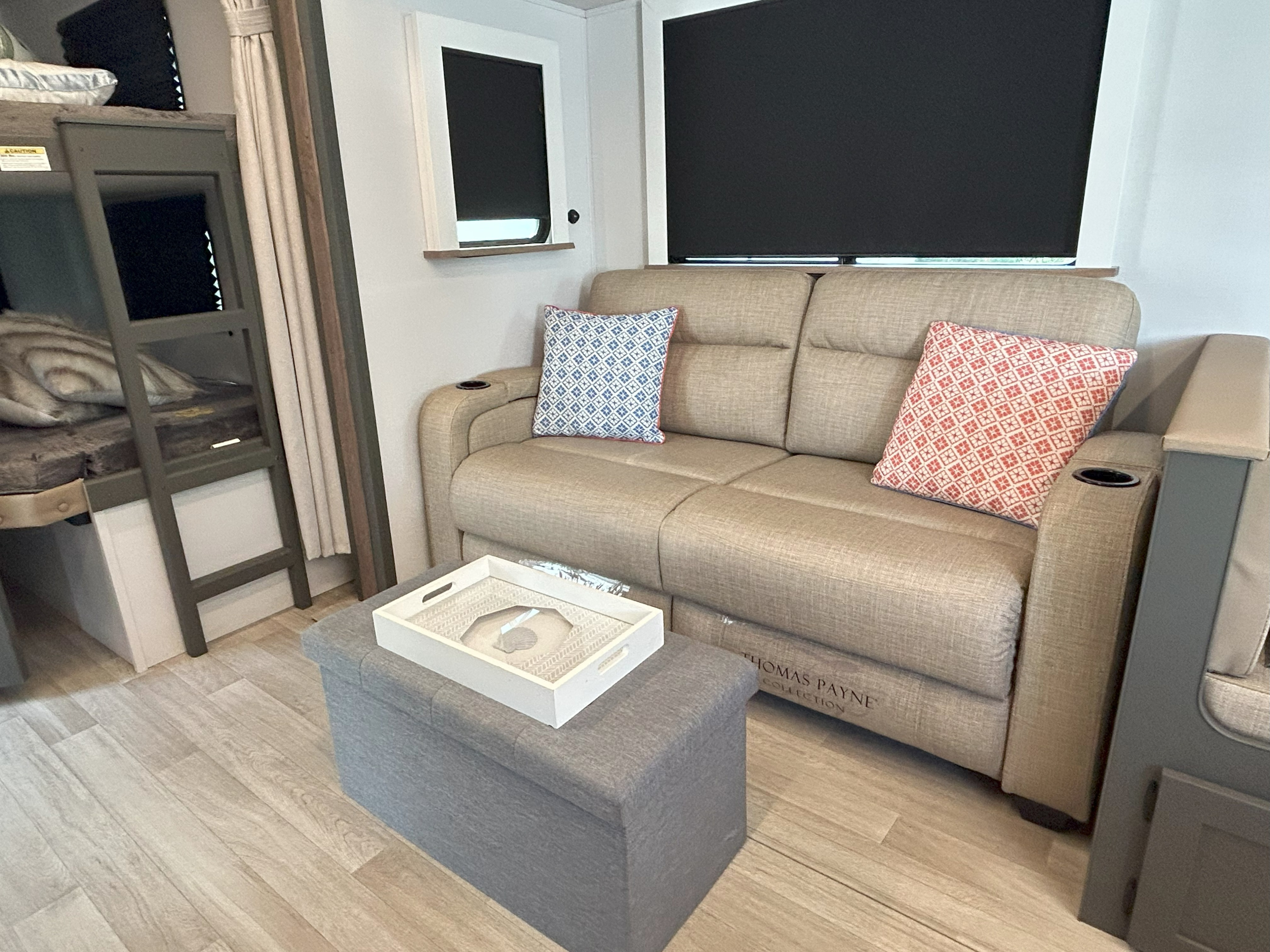 Cozy RV rental interior featuring a comfy sofa with patterned pillows, bunk beds, and a versatile storage ottoman.. Keystone RV Bullet Crossfire 2025