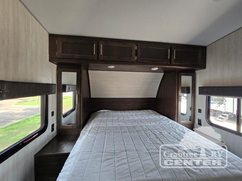 RV rental bedroom with a comfy bed, overhead storage, mirrored nightstands, and windows. Ideal for road trip adventures.. Cherokee Wolf Pack 2020