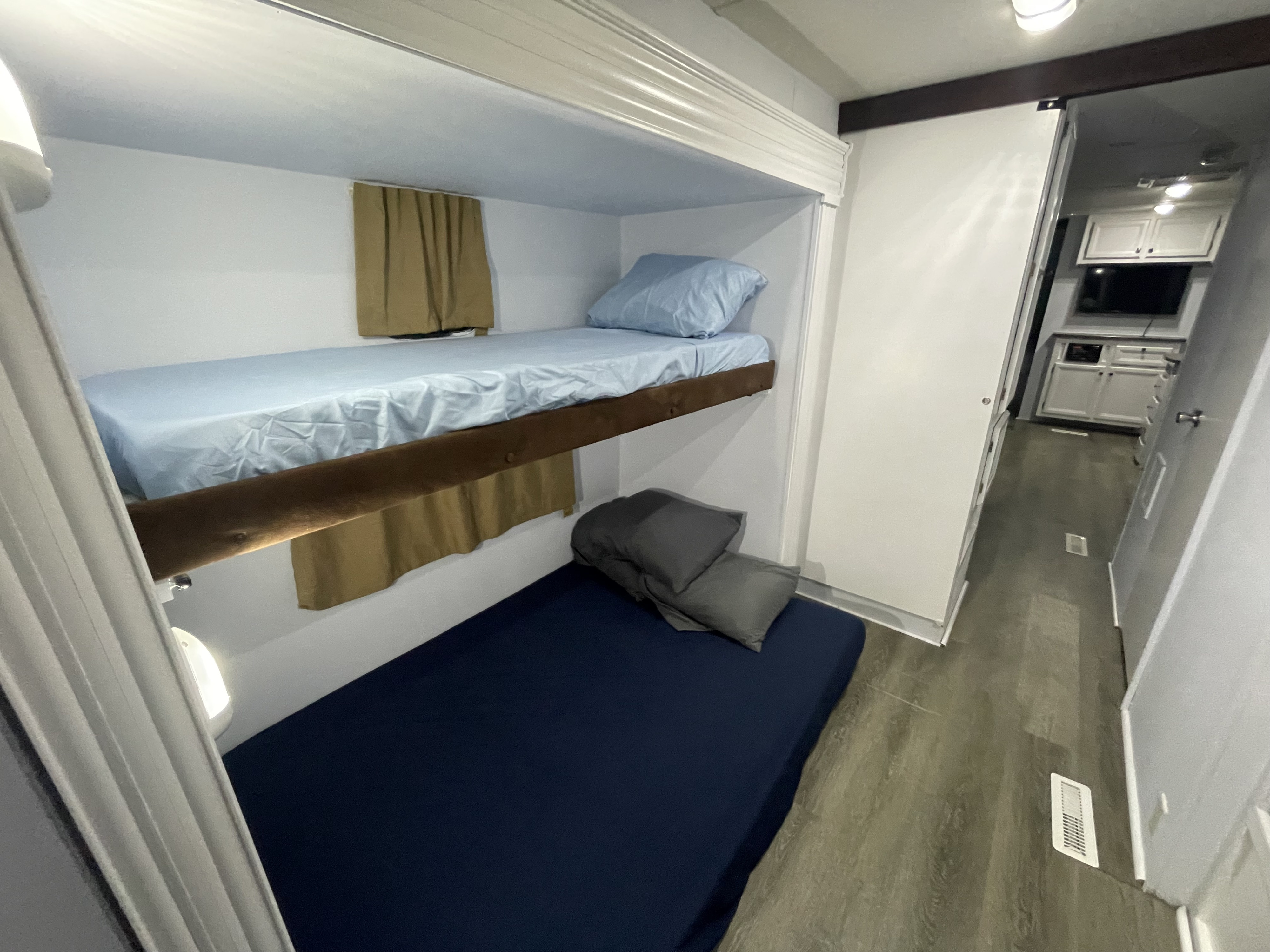 Inside this RV rental, stacked bunk beds are visible: top with light blue bedding, bottom with dark blue. A hallway is to the right.. Jayco Jay Flight 2016