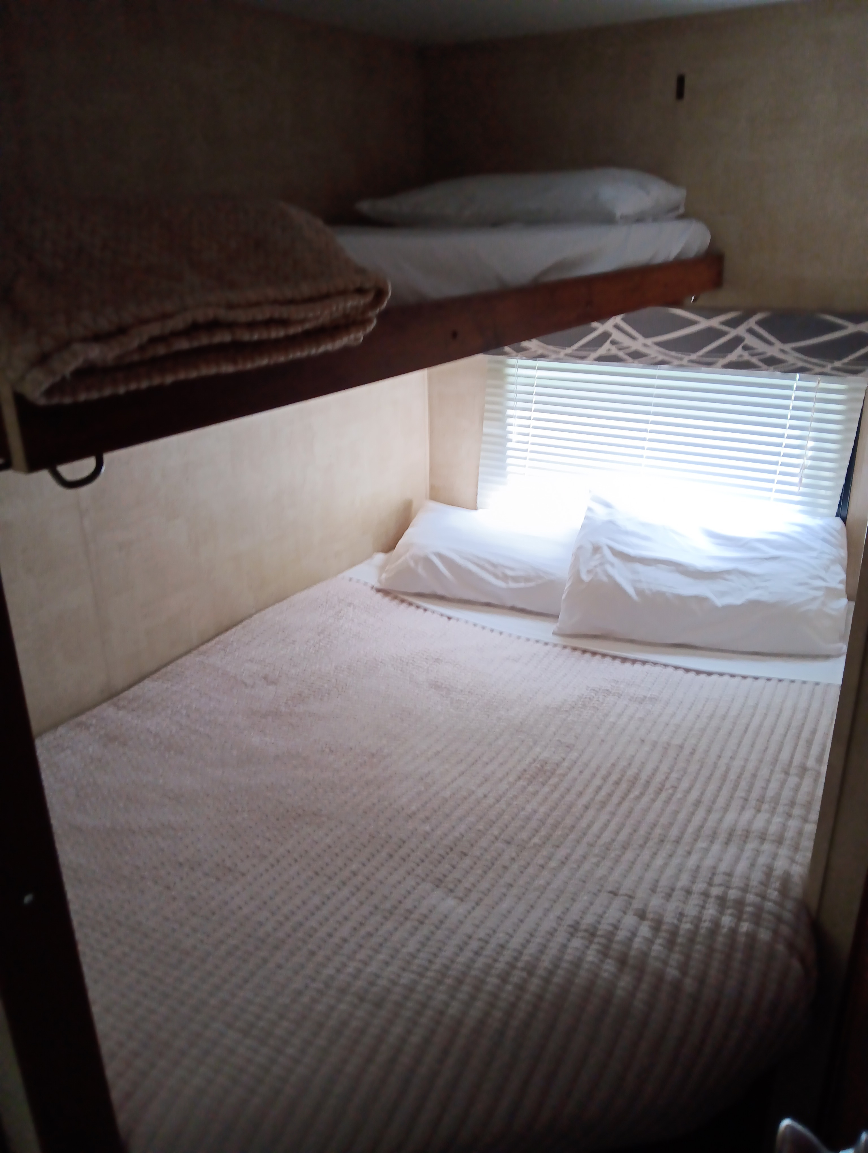 Comfortable bunk beds in an RV rental, featuring soft white pillows, quilted bedding, and window blinds.. Keystone RV Hideout LHS 2013