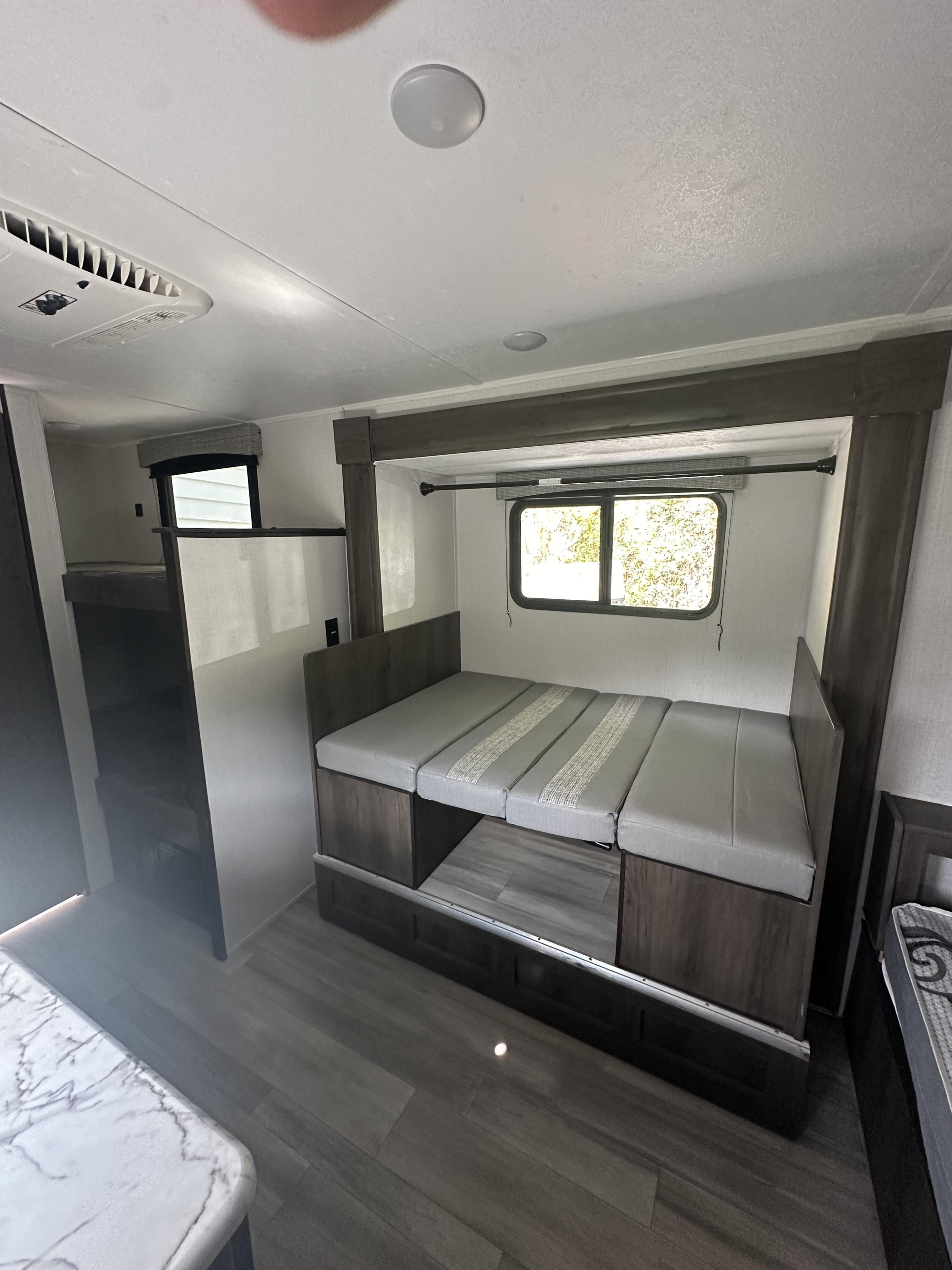 This RV rental interior showcases a convertible dinette and bunk beds, offering a modern, compact, and comfortable space for travel.. Clipper Ultra Lite 2022