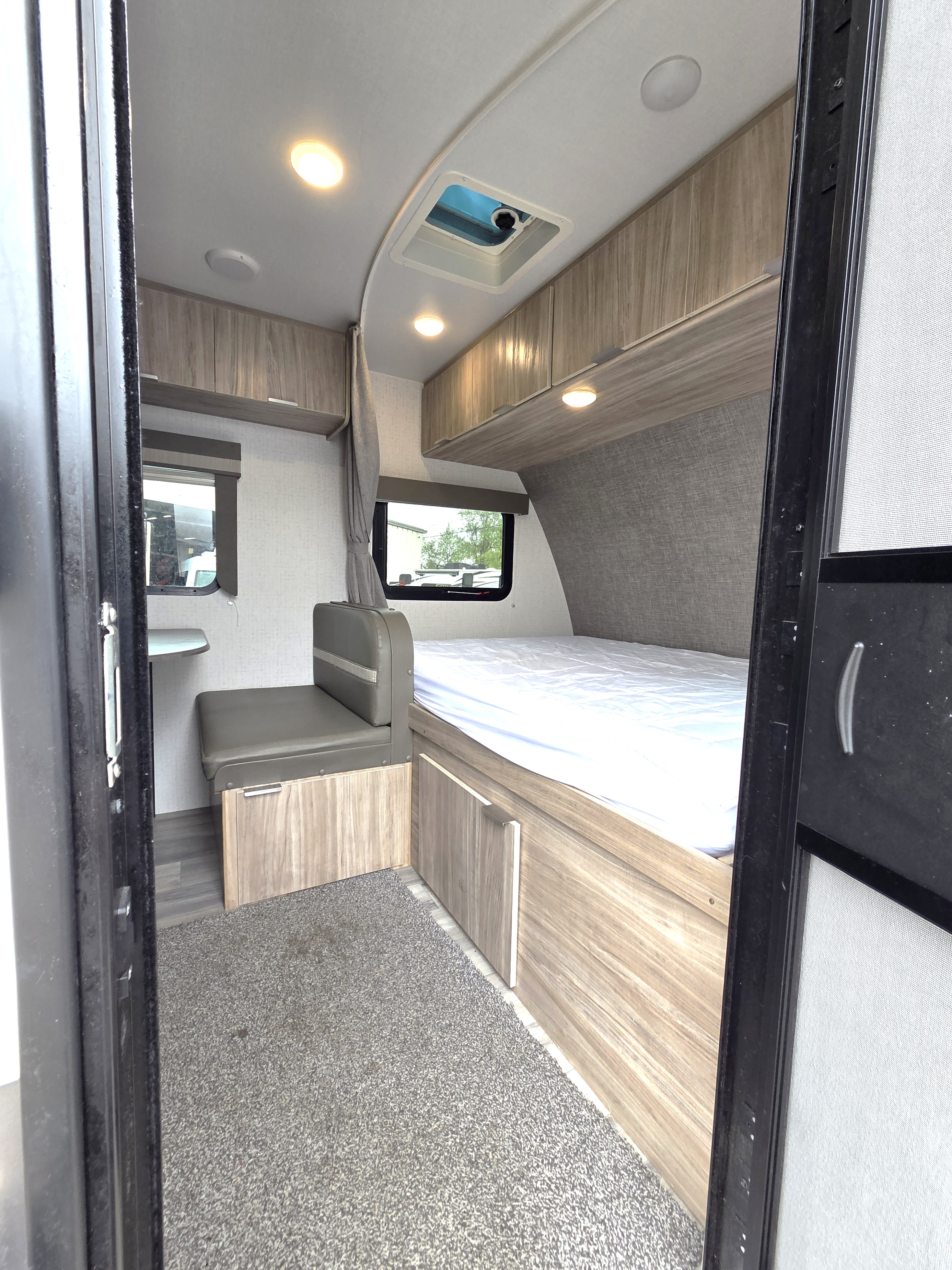 Cozy RV rental interior with a compact bed, dinette, and overhead storage. Well-lit and ready for adventure.. Winnebago Micro Minnie 2021