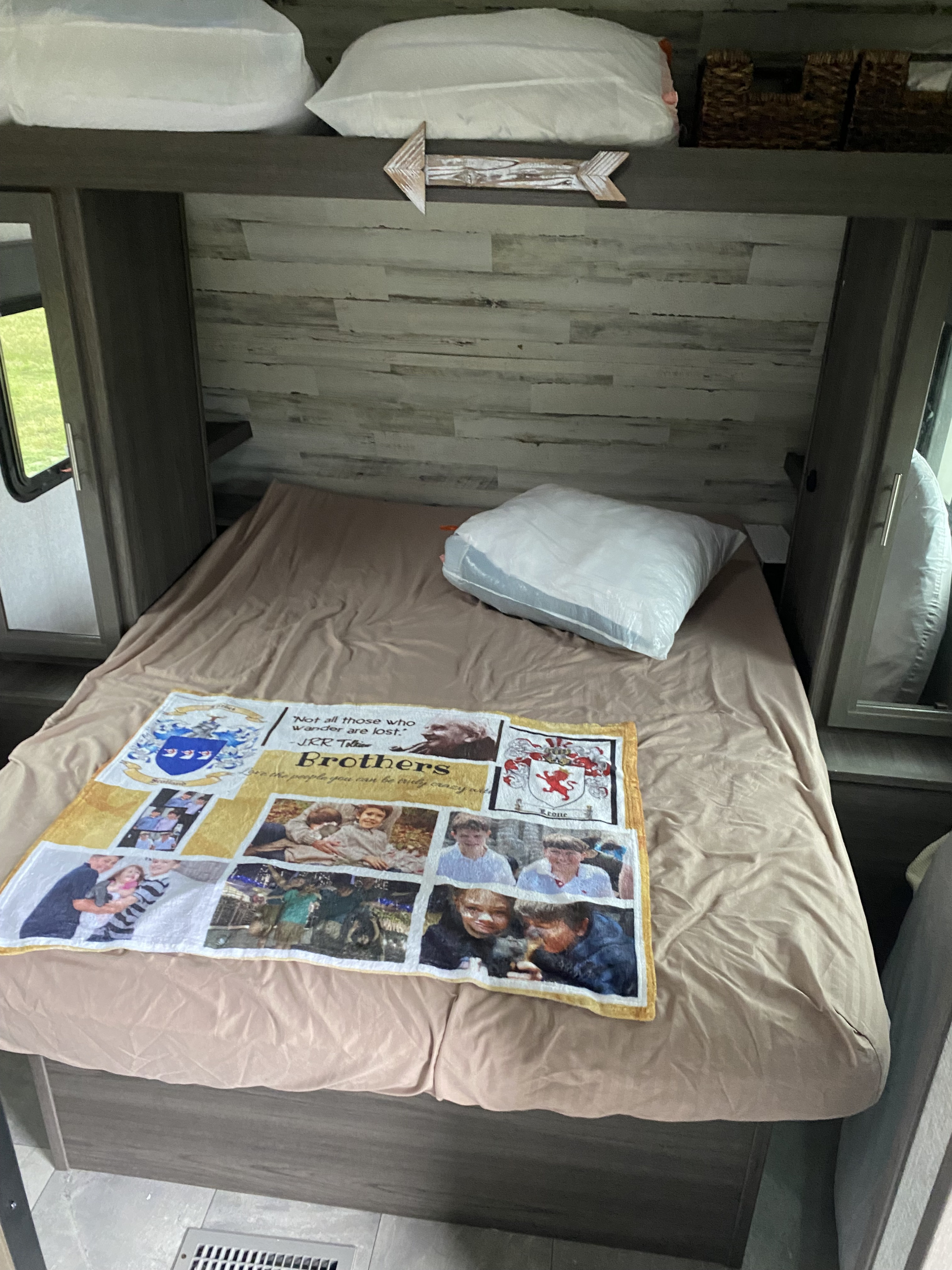 Inside an rv rental: a cozy bedroom with a personalized 'Brothers' blanket on the bed, storage, and decorative arrow.. Keystone RV Kodiak 2021
