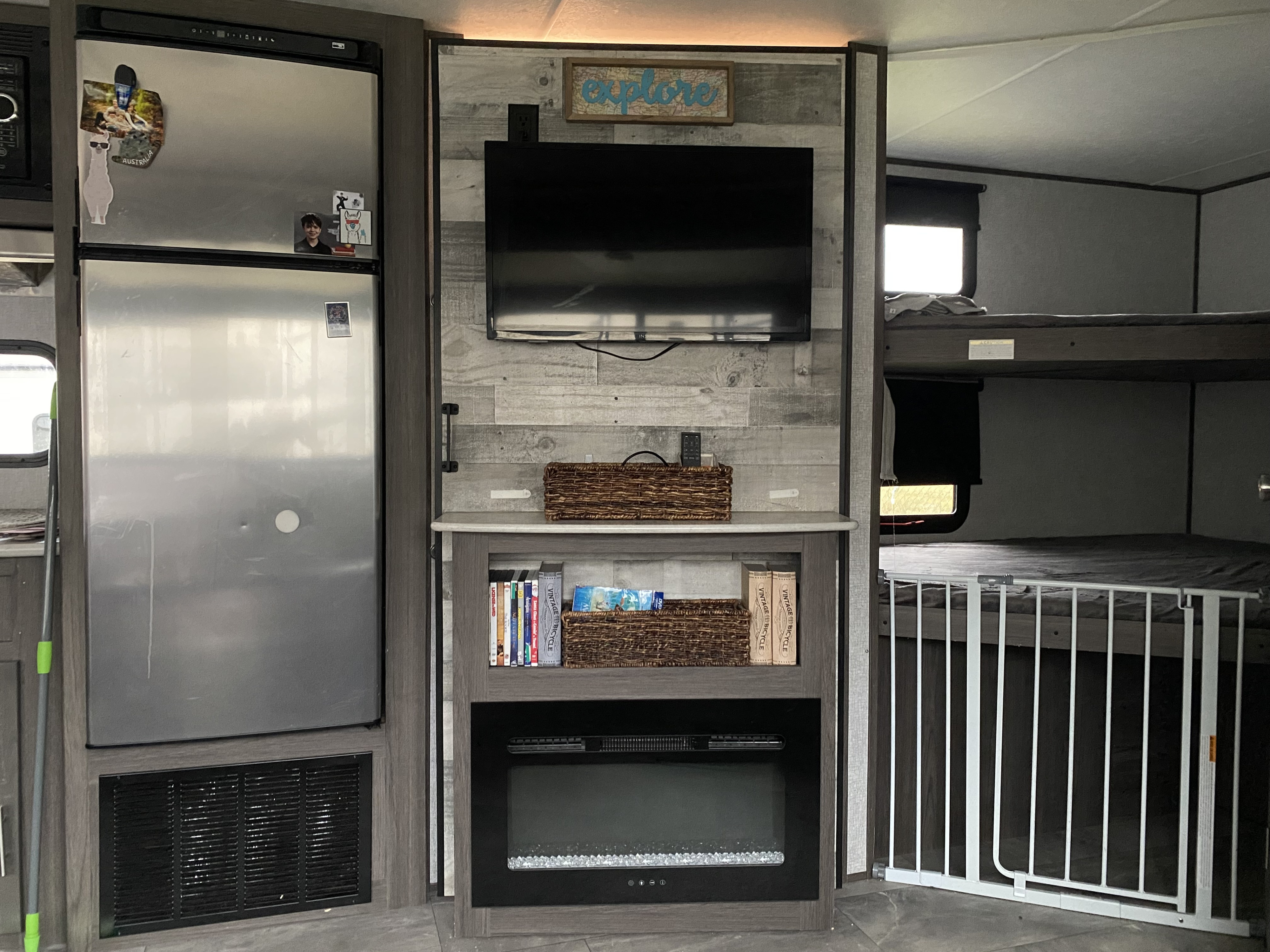 RV rental interior: fridge, TV, electric fireplace, and bunk beds with a safety gate, ideal for family adventures.. Keystone RV Kodiak 2021