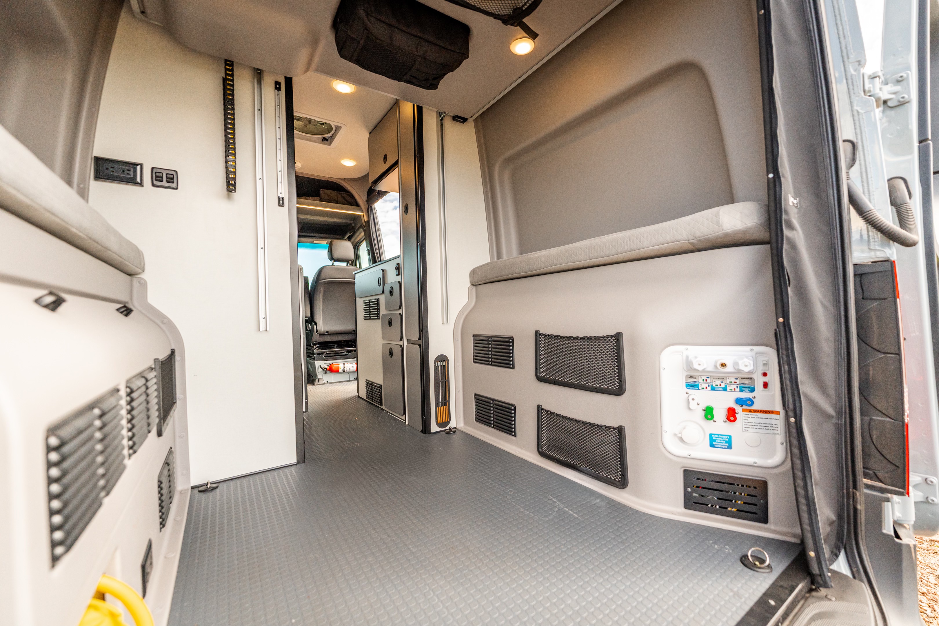 This RV rental's camper van interior features utility connections, storage, and a flexible living space with cushioned benches.. Winnebago Revel 2025