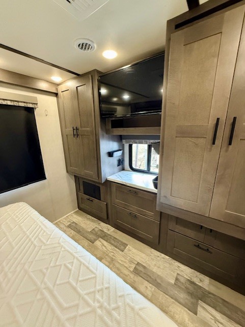 A cozy rv rental bedroom with a white textured bed, entertainment center with TV, and ample wood-toned storage cabinets.. FR3 FR3 Motorhome 2021