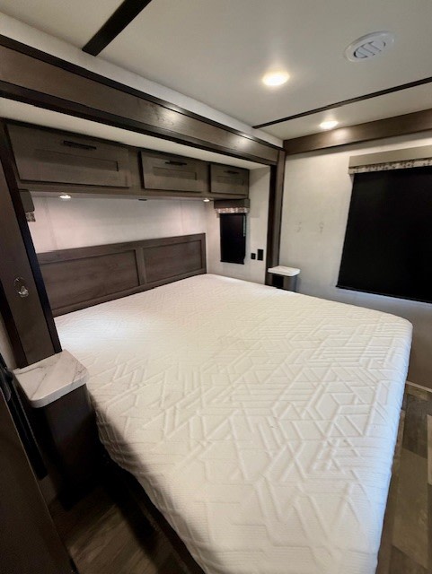 Modern RV rental bedroom featuring a large white bed, sleek dark wood cabinets, and bright ceiling lights for a comfortable journey.. FR3 FR3 Motorhome 2021