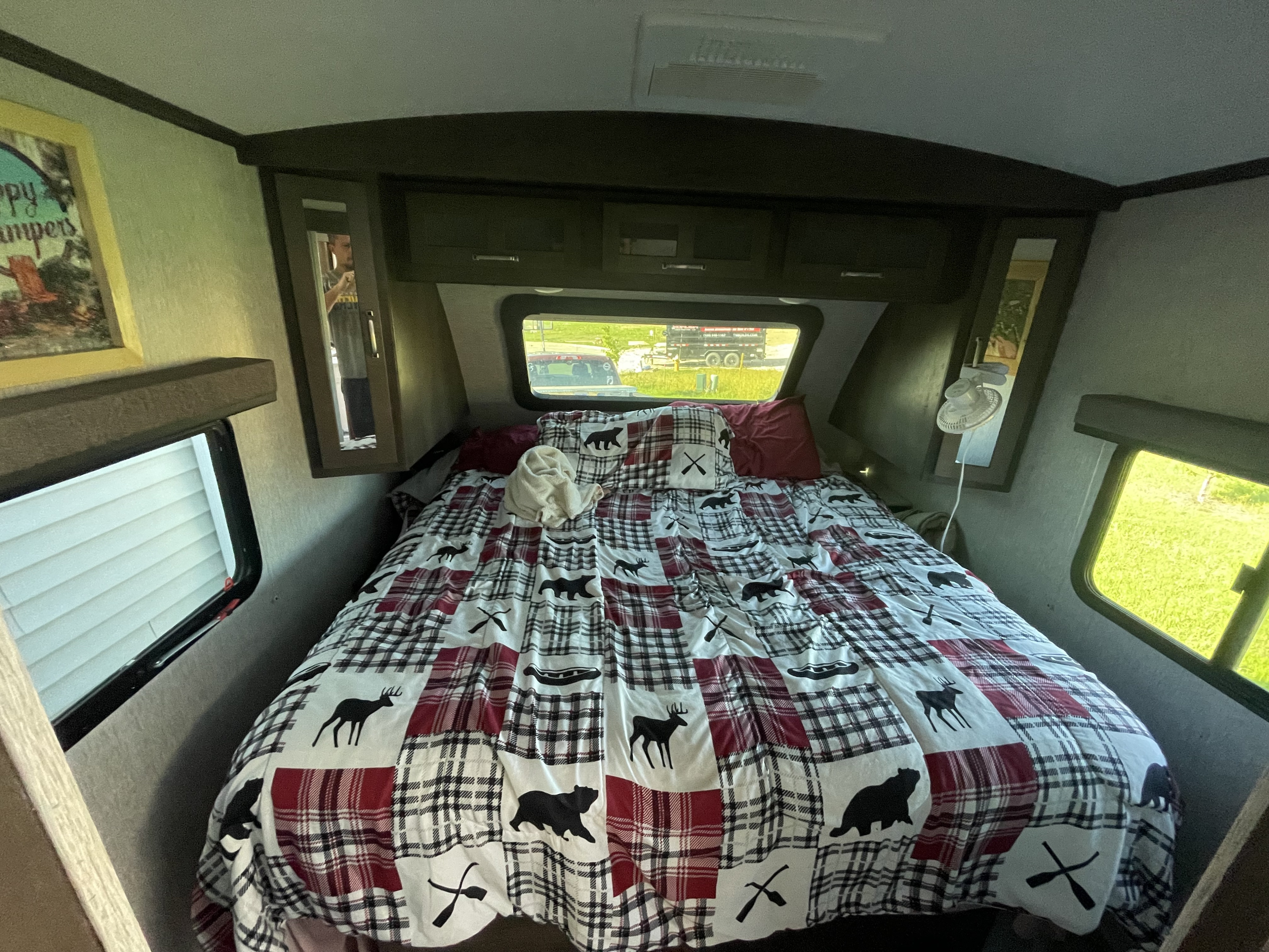 RV rental bedroom with a cozy plaid bed, featuring animal & outdoor motifs, and bright windows.. Dutchmen 2903bh 2020