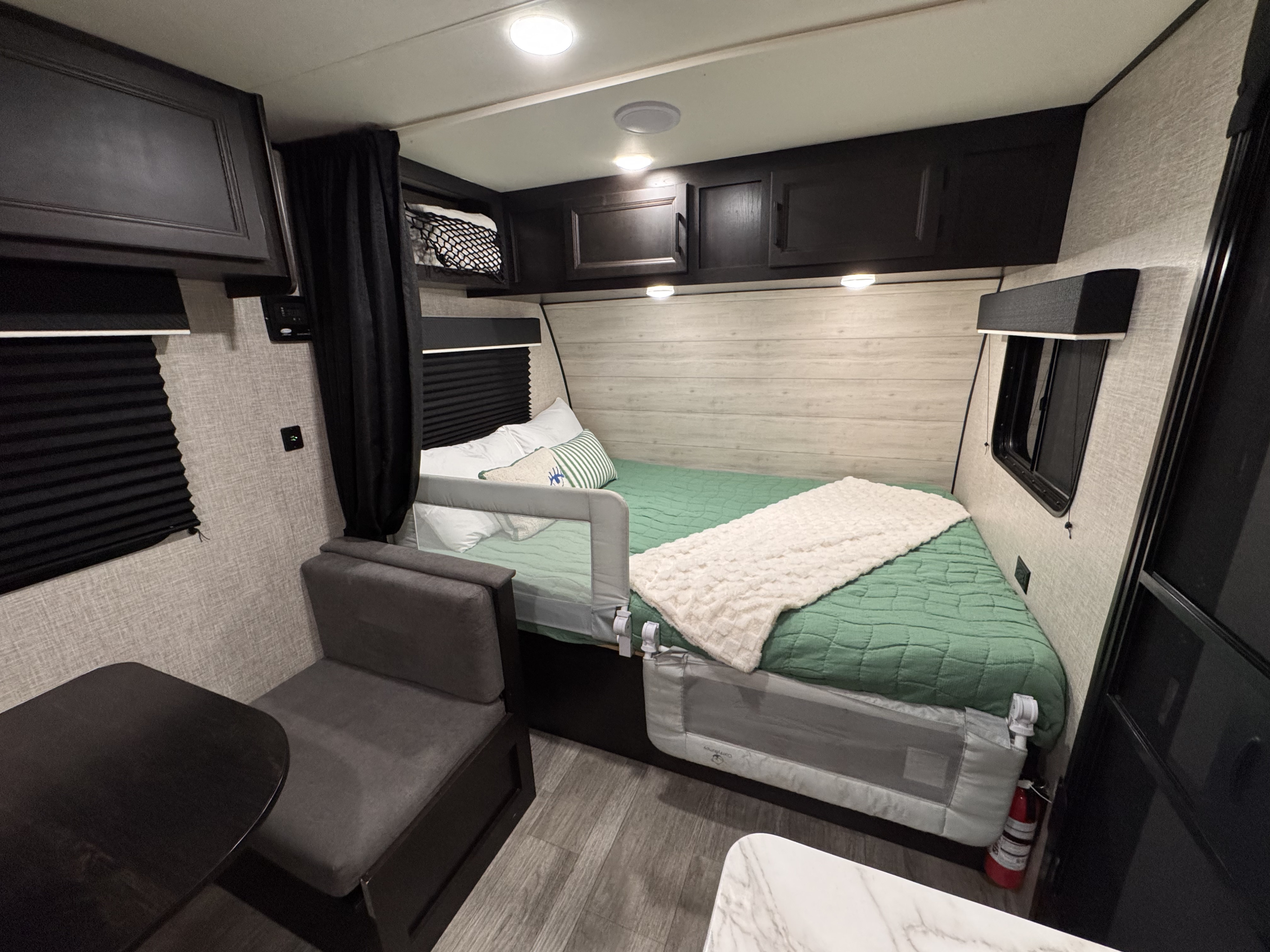 RV rental sleeping area with safety rails, overhead storage, and adjacent dinette, offering a cozy and functional interior.. Jayco Jay Flight SLX STX Edition 2023