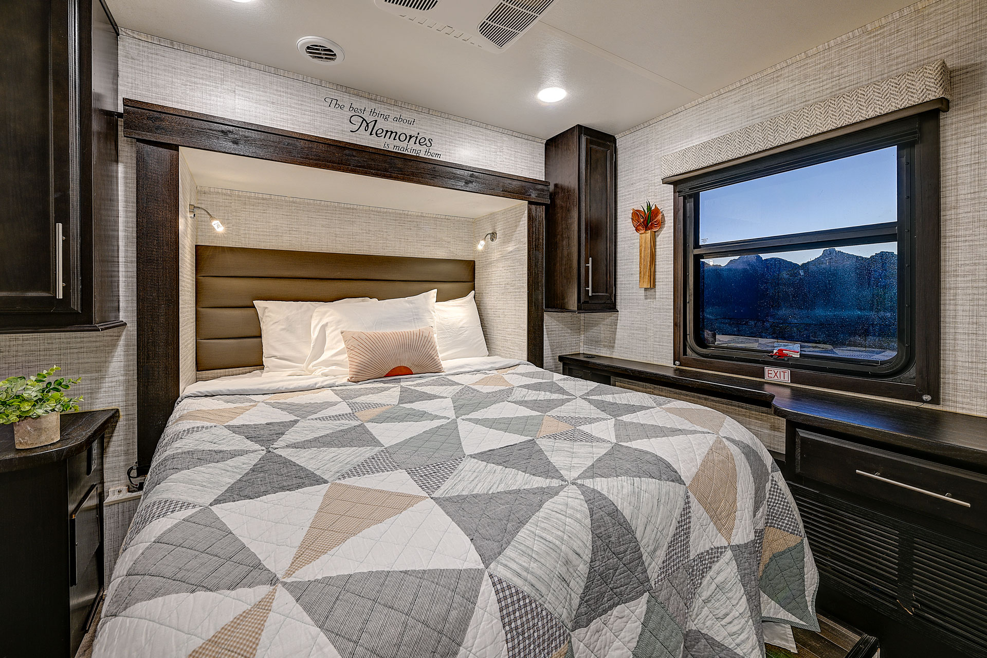Cozy RV rental bedroom with a comfortable bed, warm lighting, and a window showcasing scenic mountain views.. Entegra Coach Odyssey 2024