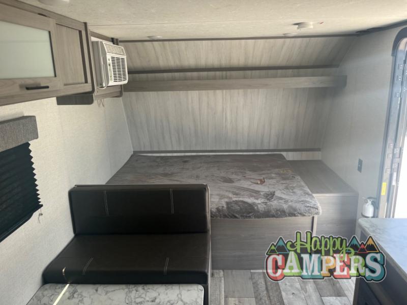 Discover this cozy RV rental interior with a bed, dinette, AC unit, and overhead storage, perfect for road trips.. Dutchmen Coleman Lantern LT 2023