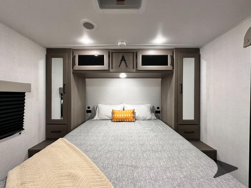 Cozy RV rental bedroom with a comfortable bed, stylish overhead storage, and modern interior lighting.. Grand Design Transcend 2026