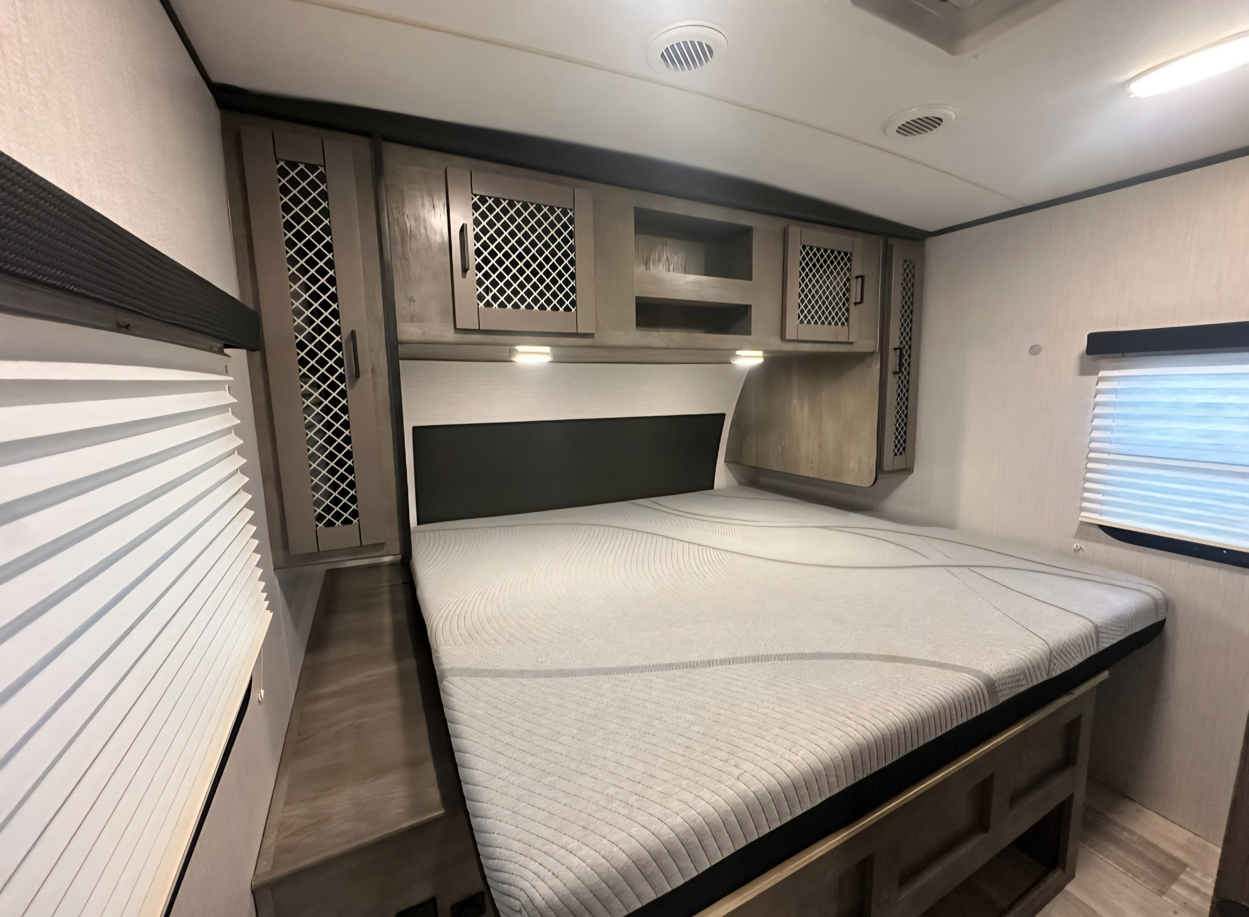 Comfortable RV rental bedroom with a plush mattress, overhead storage, ambient lighting, and window blinds.. Heartland RVs North Trail 2021
