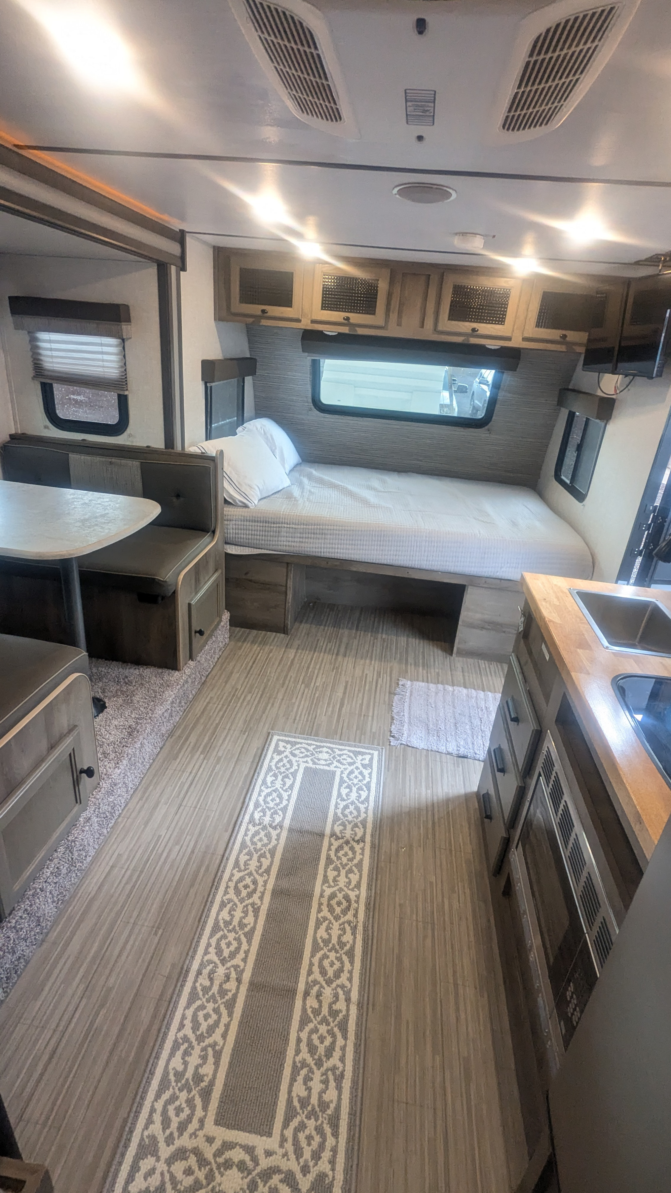 Inside an RV rental, a compact living space with a dining booth, bed, and small kitchen. Ready for your road trip!. Forest River Surveyor Legend 2021