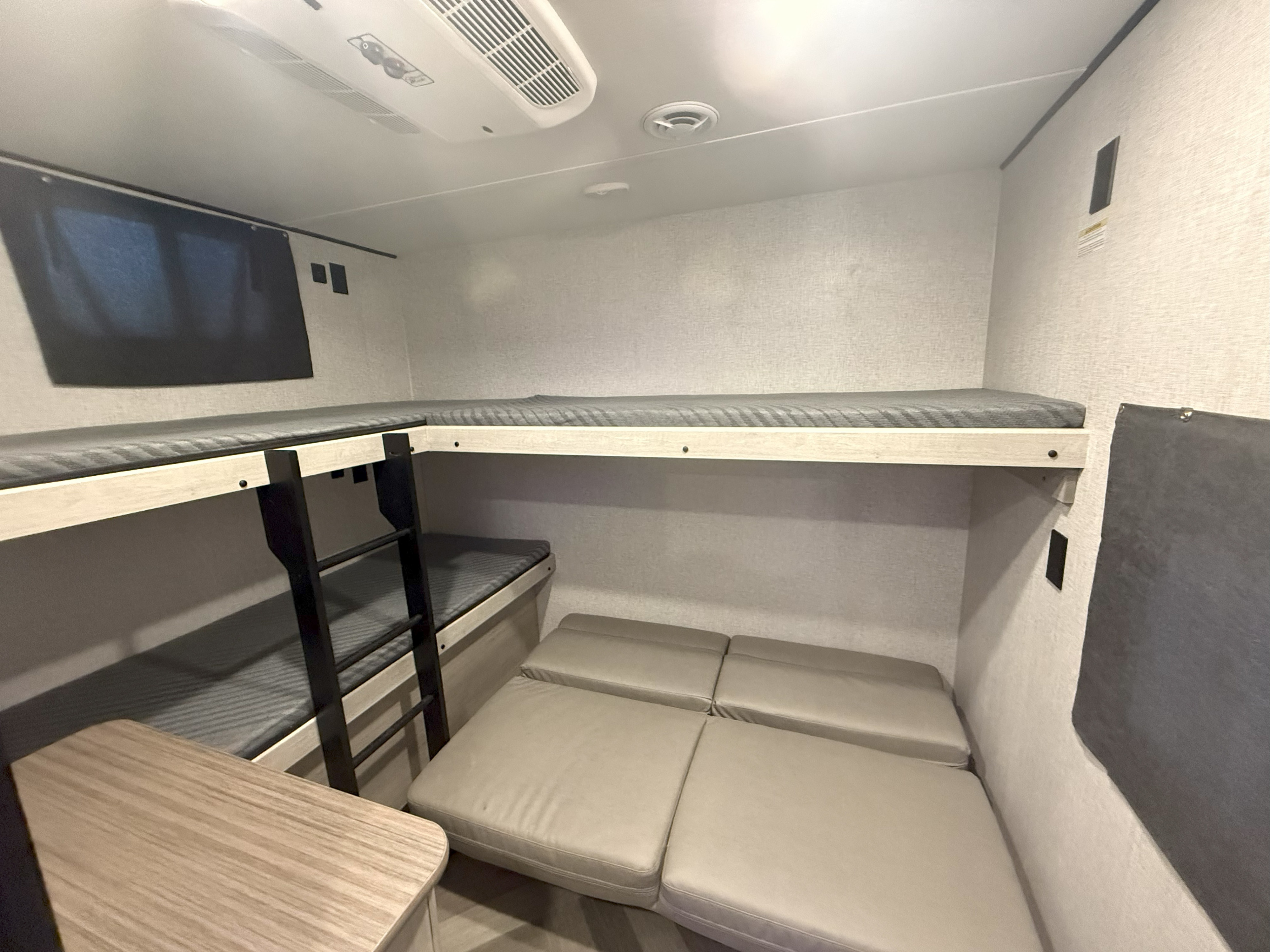 RV rental interior featuring comfortable bunk beds with a ladder, and light-colored modular seating.. Crossroads RV Zinger 2024