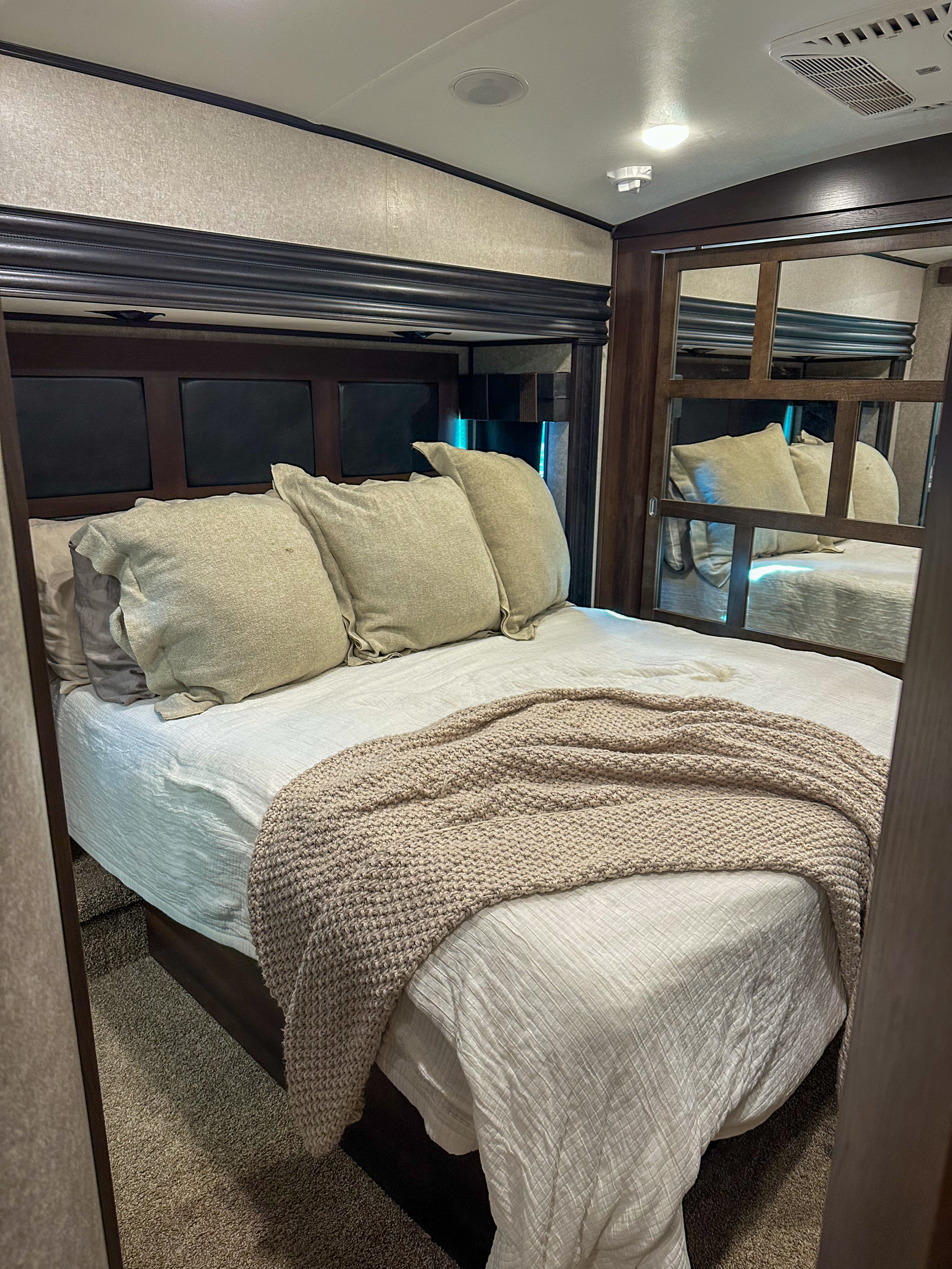 Cozy RV rental bedroom with a comfortable bed, mirrored closet, and ceiling amenities for a relaxing trip.. Jayco North Point 2018