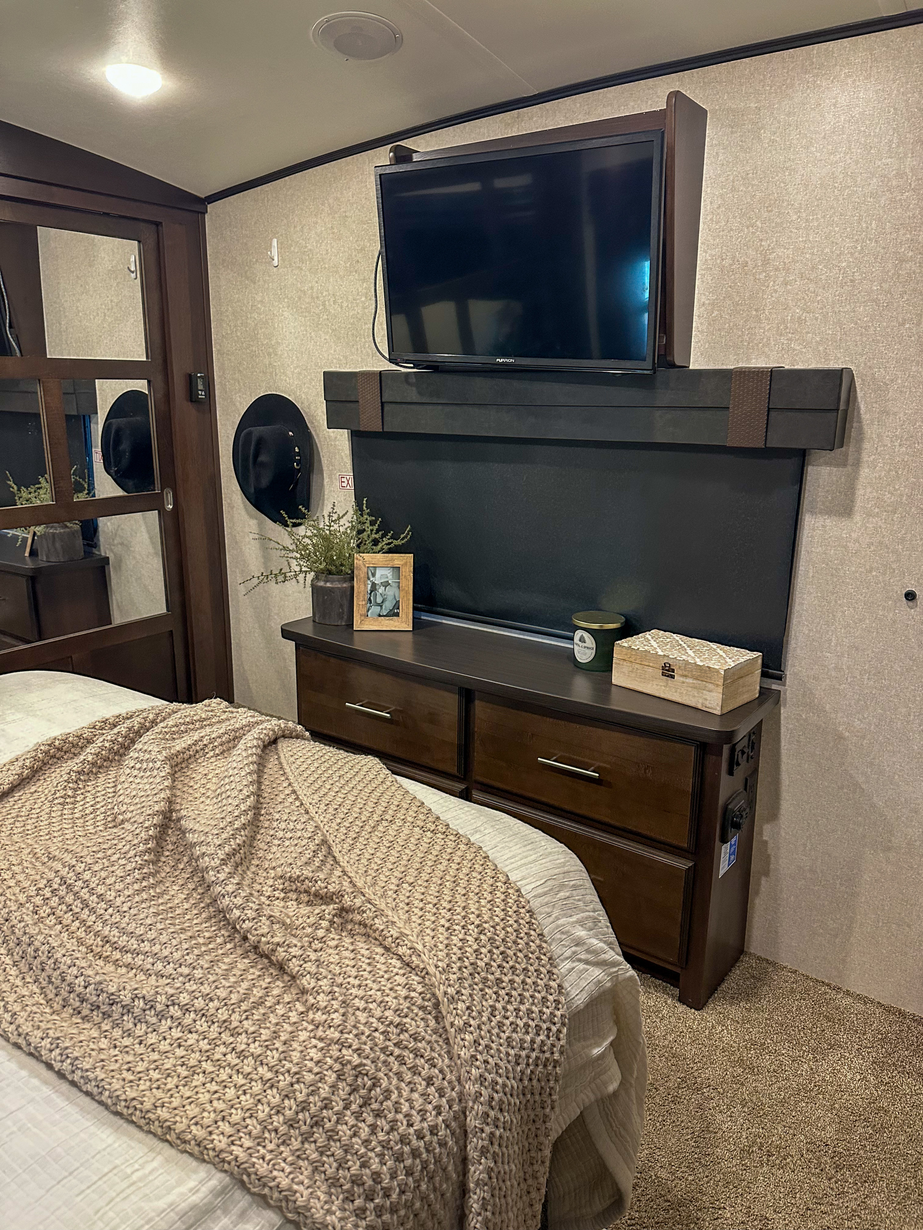 Comfortable RV rental bedroom interior with a TV, dresser, and a soft knit blanket on the bed.. Jayco North Point 2018