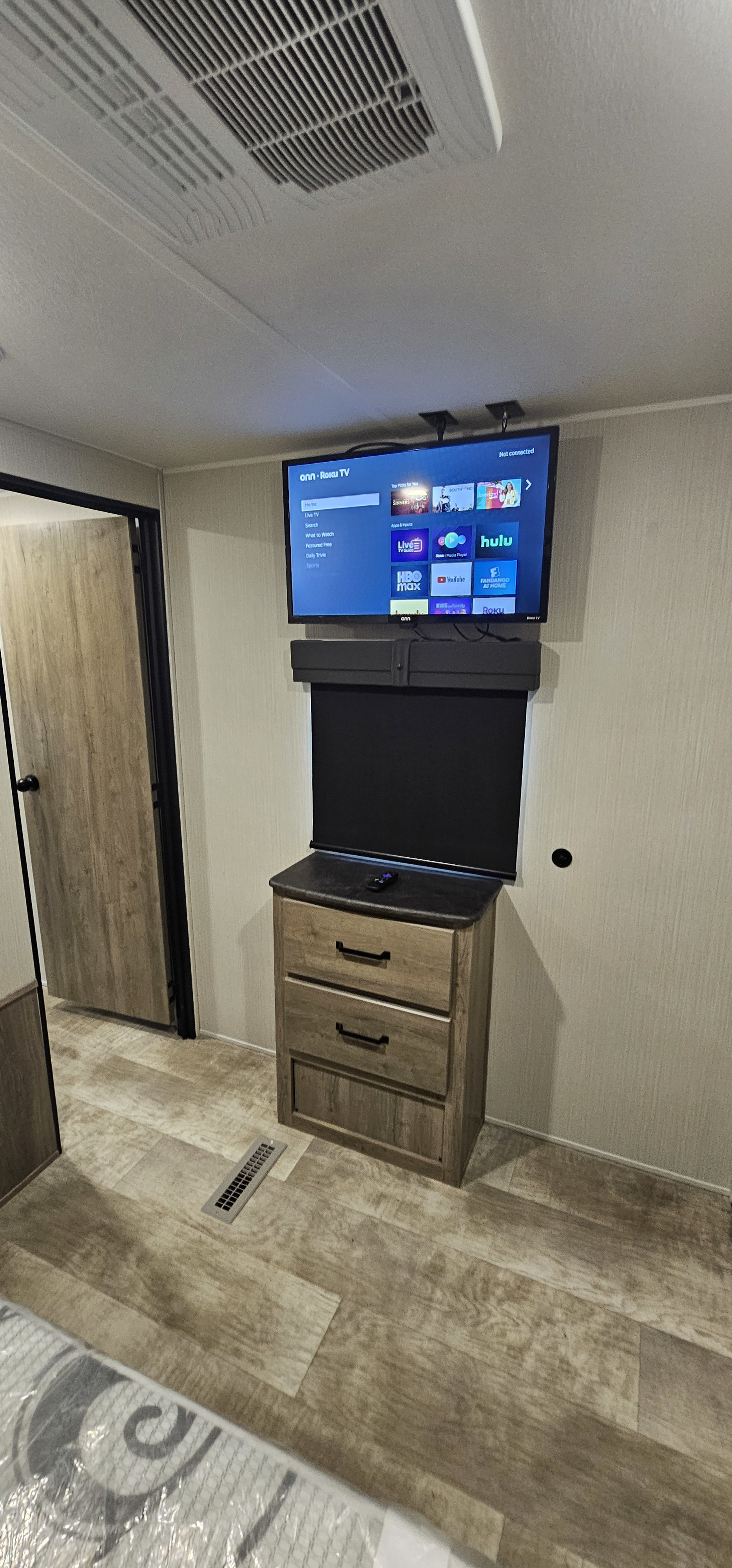 Inside an RV rental: a wall-mounted Roku TV with streaming apps like Hulu, a dresser below, and wood-look flooring.. Forest River Palomino Puma 2024