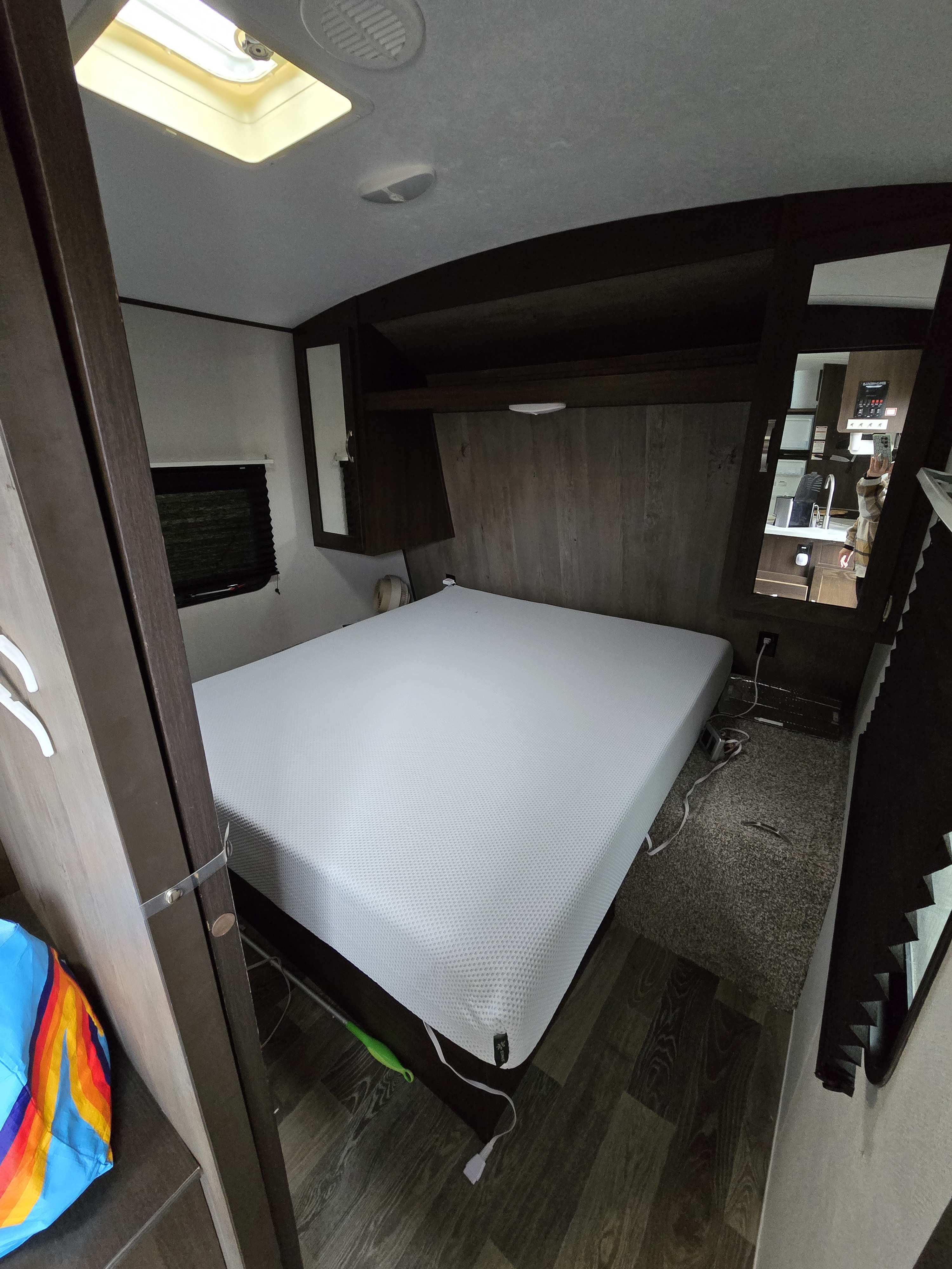Cozy RV rental bedroom featuring a fresh white mattress, dark wood accents, and integrated storage. Perfect for road trips.. Keystone RV Springdale 2020