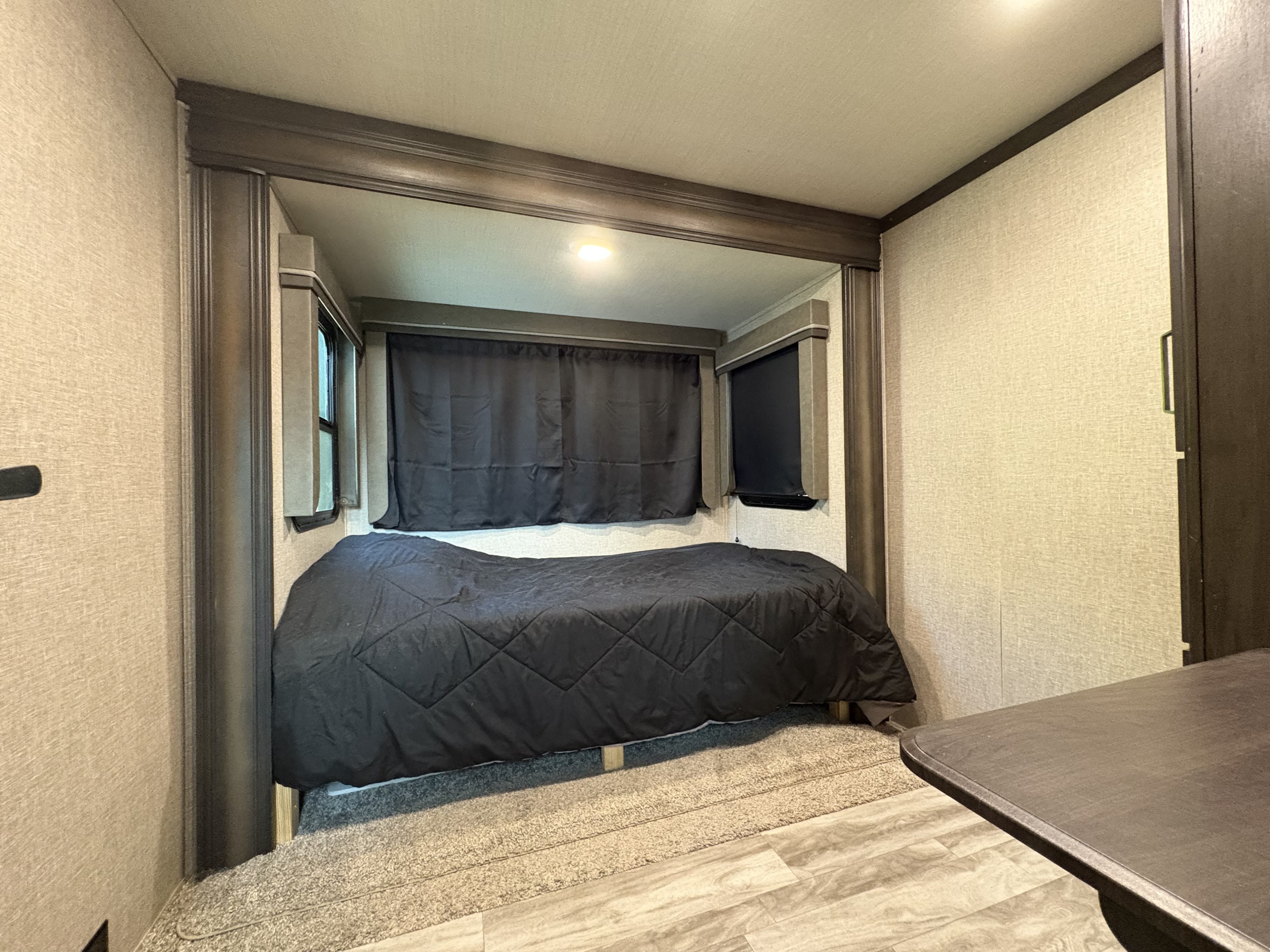 This RV rental features a cozy bedroom with a comfortable bed, window shades, and a rug, offering a welcoming travel space.. Grand Design Reflection 2023