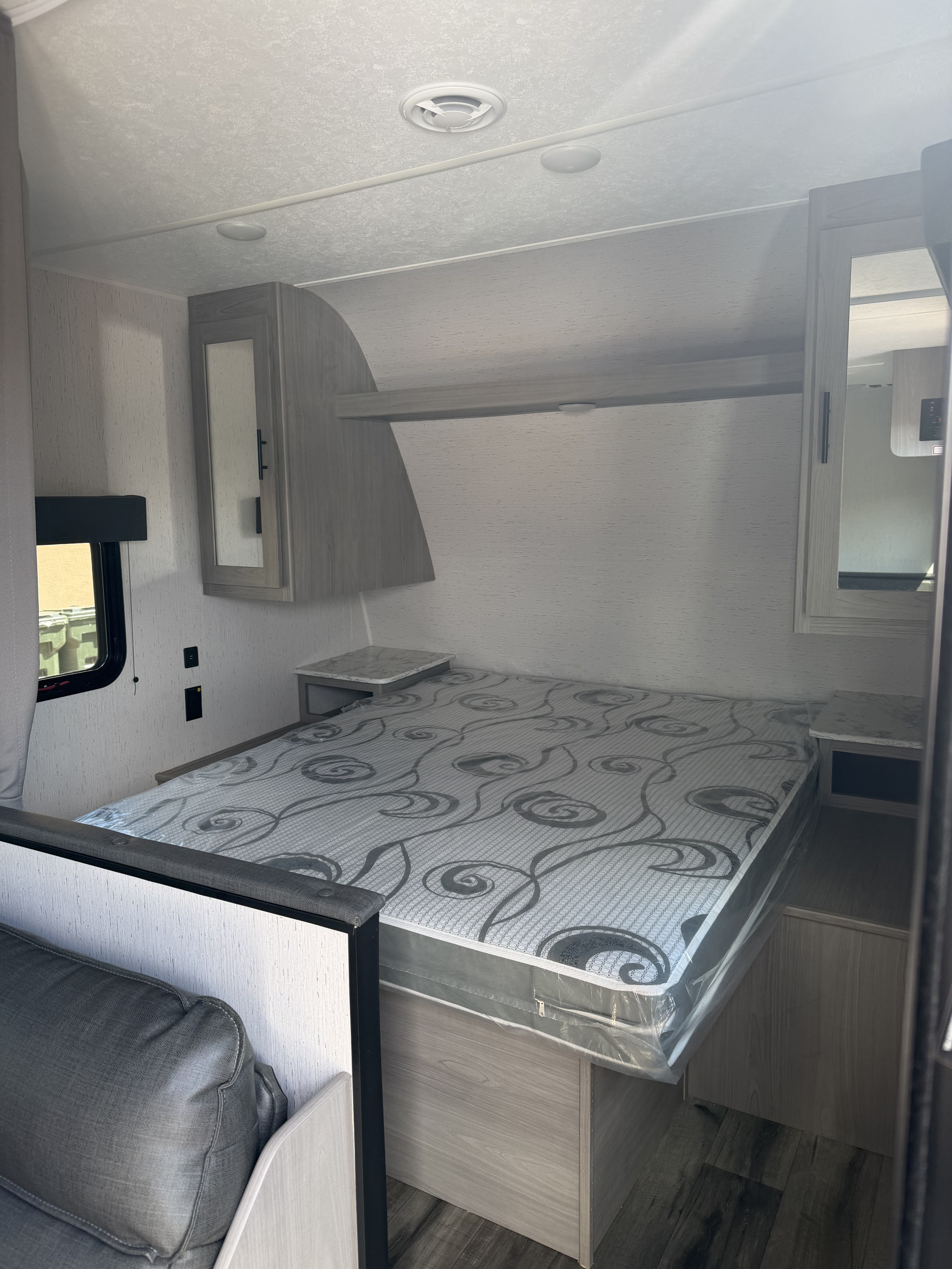 Bright RV rental bedroom showcasing a new mattress, overhead cabinets, window, and dual nightstands.. Dutchmen Coleman Lantern LT - 274BHWE 2024
