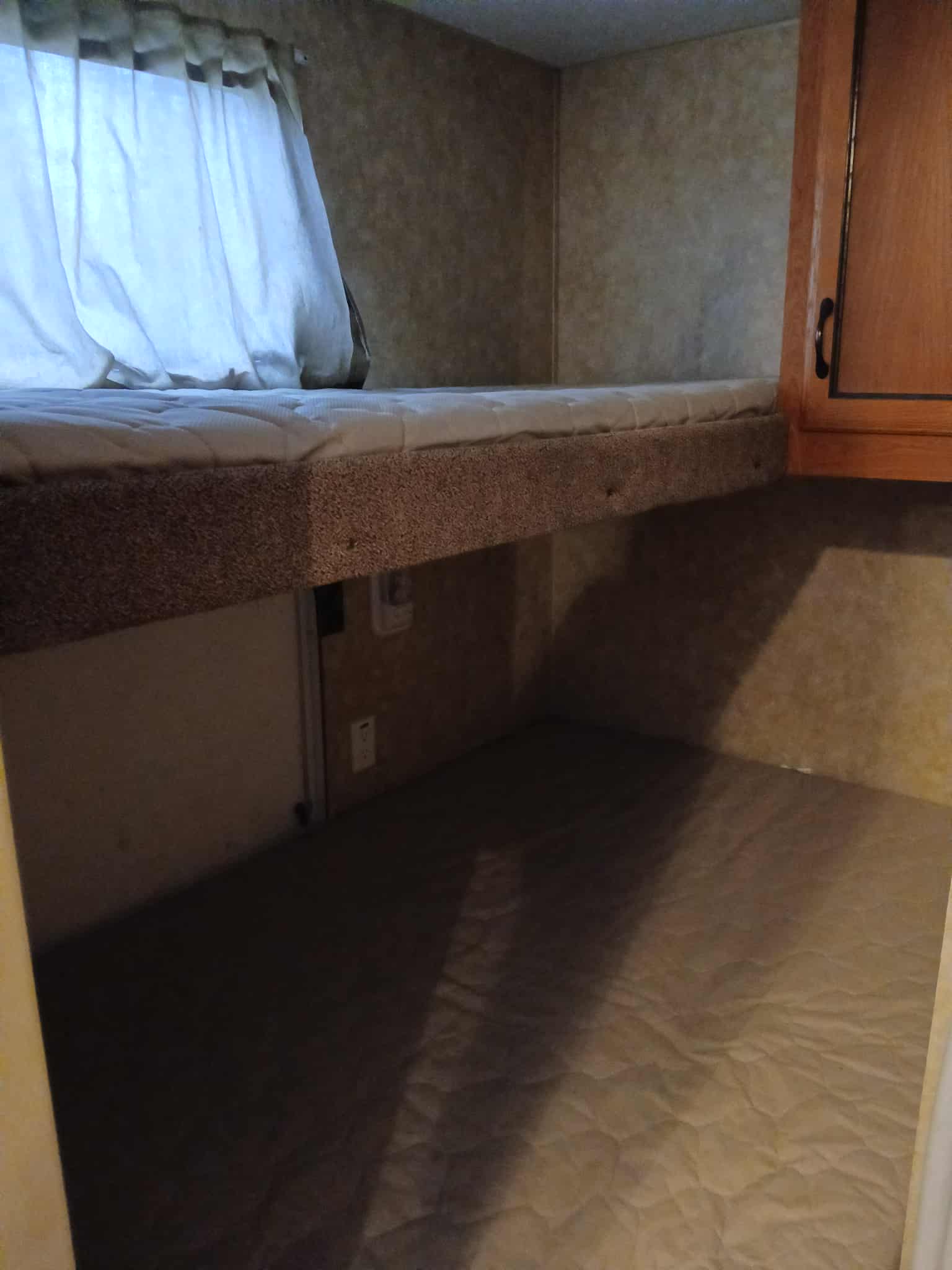 Cozy RV rental bunk bed with a comfortable mattress, curtains on the window, and a lower sleeping area.. Forest River Coachmen Catalina 2011