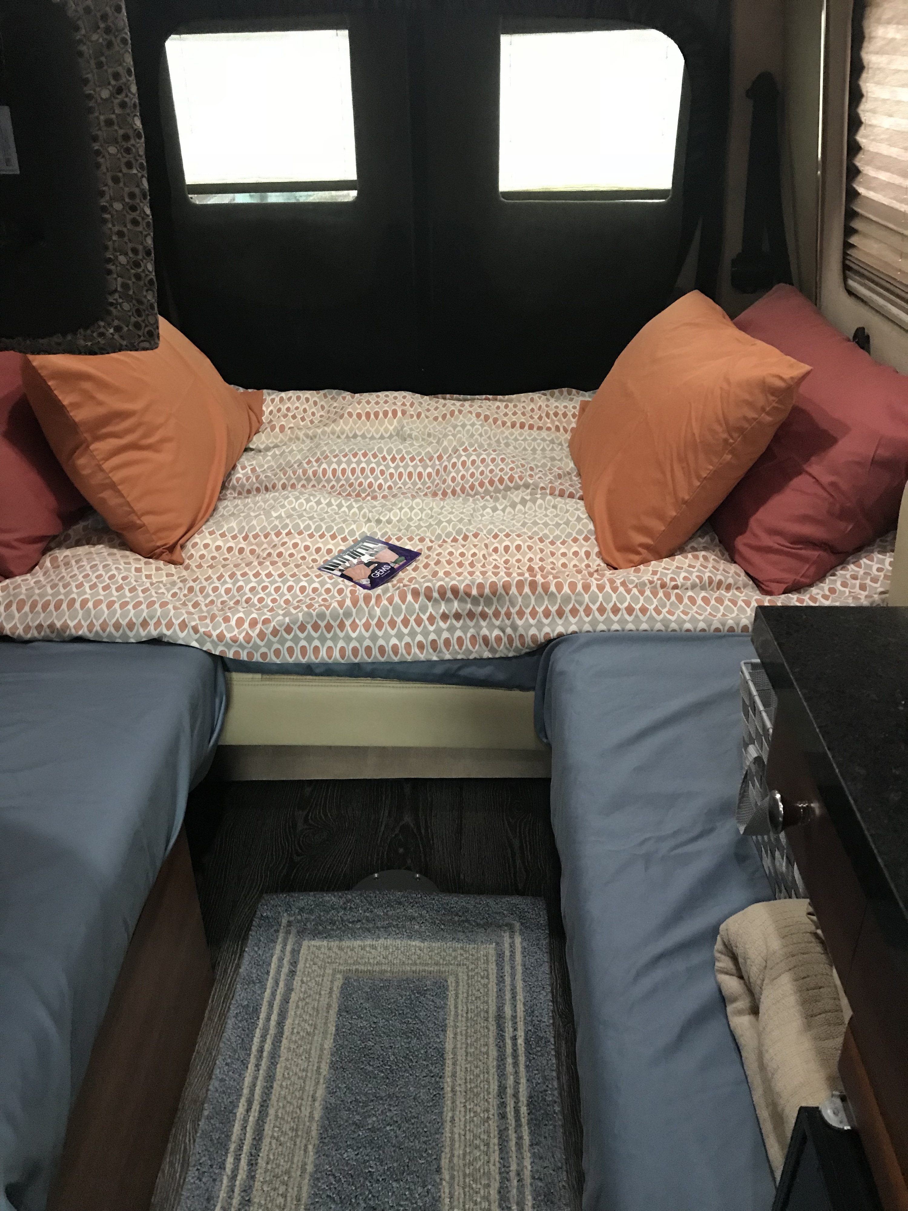 Cozy rv rental interior: main bed with patterned blanket, orange pillows, and two blue side beds, perfect for travel.. Roadtrek Roadtrek Class B 2016
