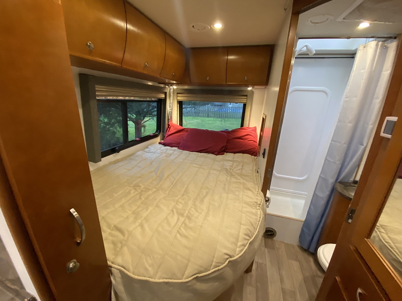 Cozy RV rental bedroom with a comfortable bed, overhead storage, and a connected bathroom for convenient travel.. Leisure Travel Van Unity CB 2013