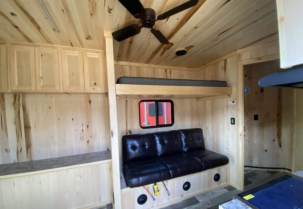 This rustic RV rental interior features wood paneling, a ceiling fan, bunk bed, sofa, and overhead storage.. LEGEND OUTDOORS 8621NDA 2024