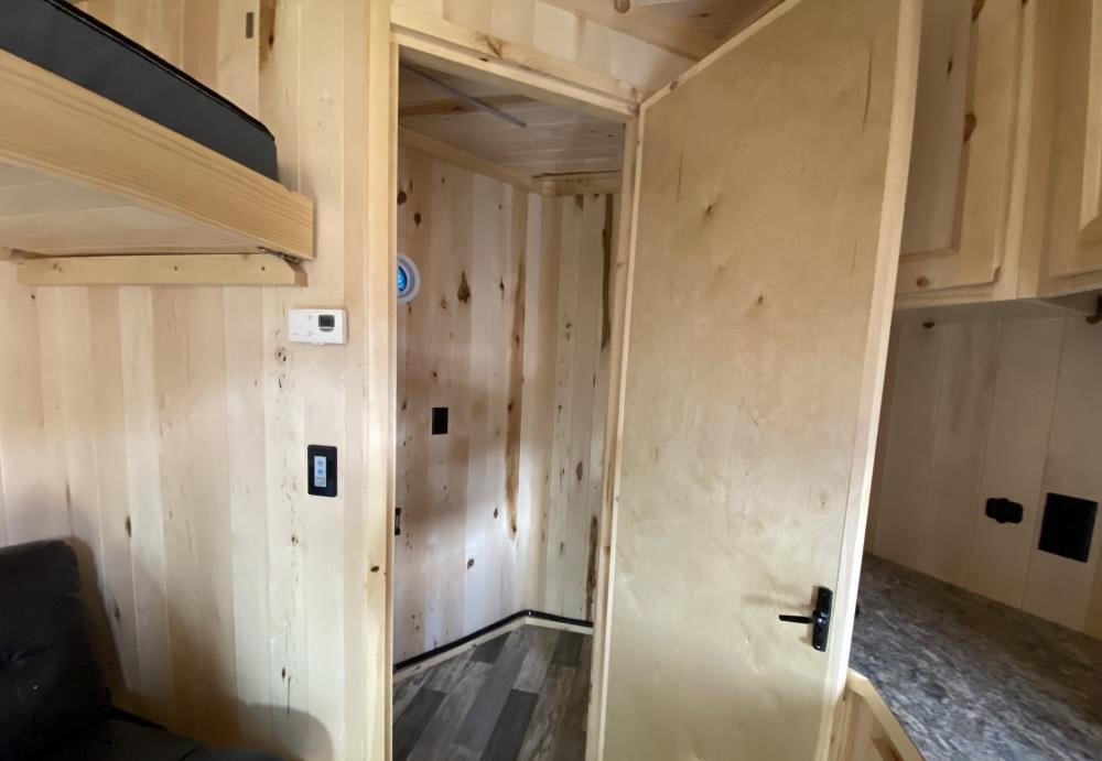 Cozy RV rental interior with light wood walls, showing a bunk bed, open doorway to another section, and storage cabinets.. LEGEND OUTDOORS 8621NDA 2024