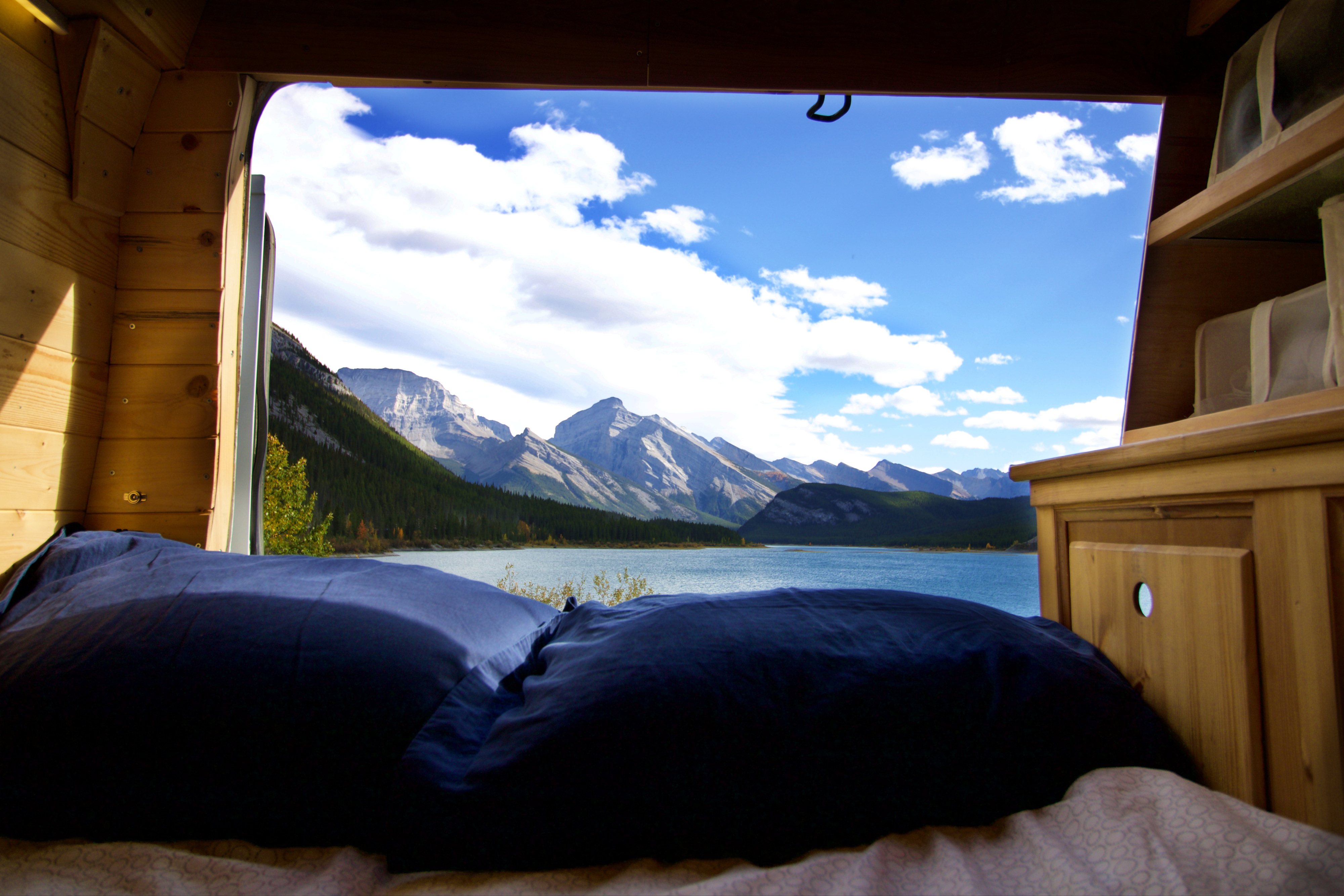 Enjoy a serene mountain lake view from a cozy **RV rental** bedroom. Perfect for nature-filled **van life** adventures!. Ford Econoline 2009