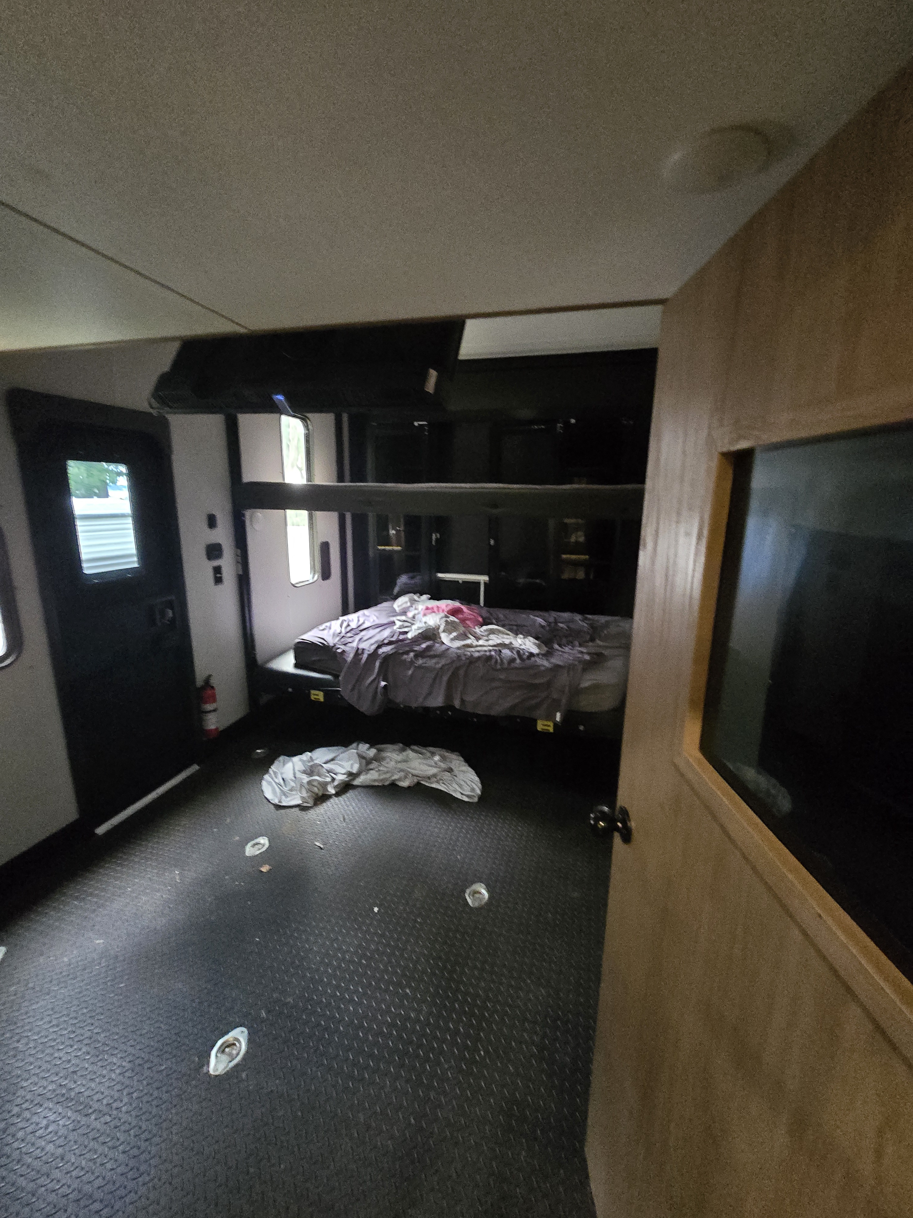 RV rental interior: A toy hauler's garage area with a lower bed, upper bunks, and dark, textured utility flooring.. Forest River Cherokee Wolf Pack Toy Hauler 2024