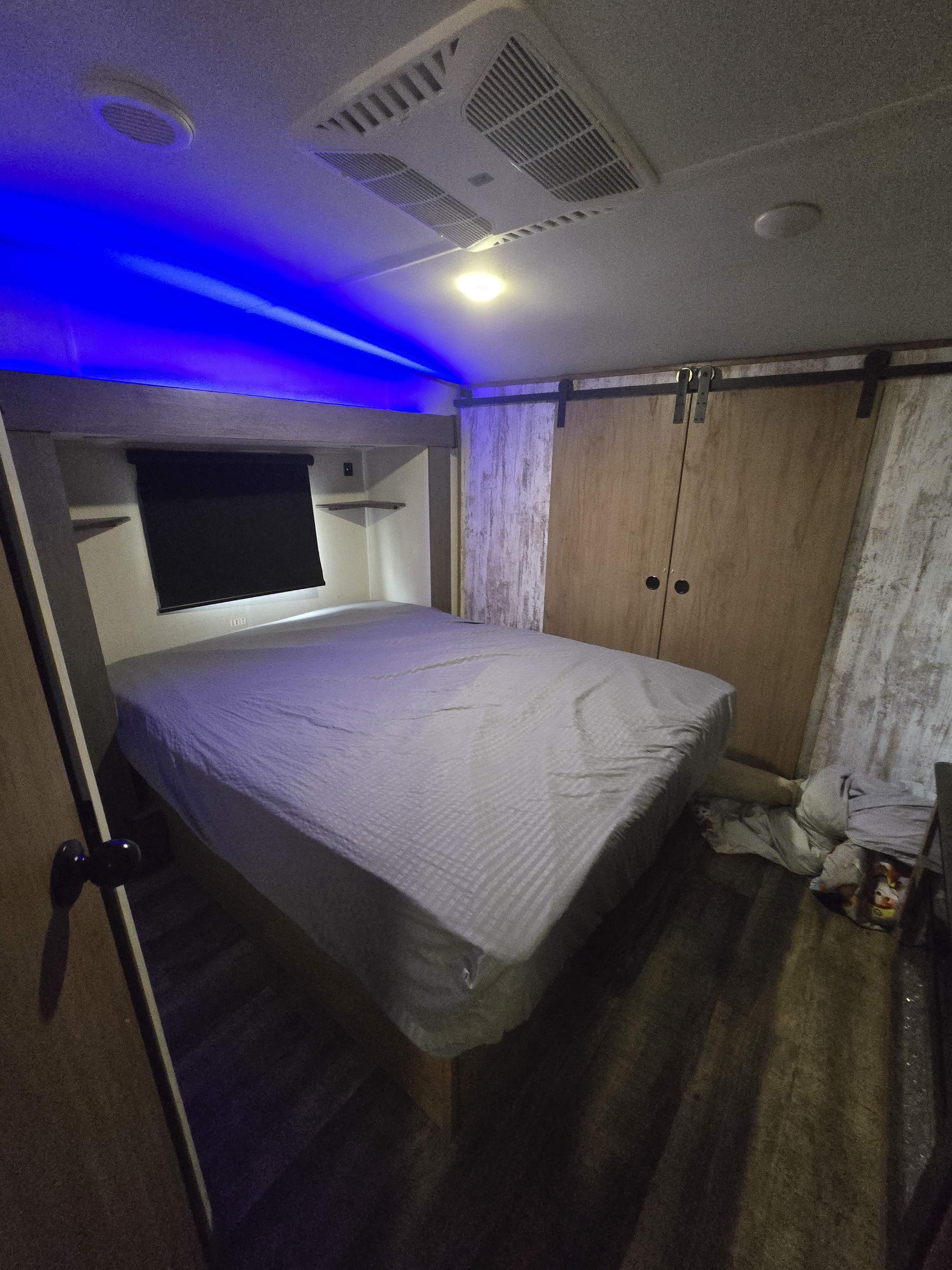 This rv rental bedroom features a comfortable bed, blue accent lighting, AC, and a sliding door closet.. Forest River Cherokee Wolf Pack Toy Hauler 2024
