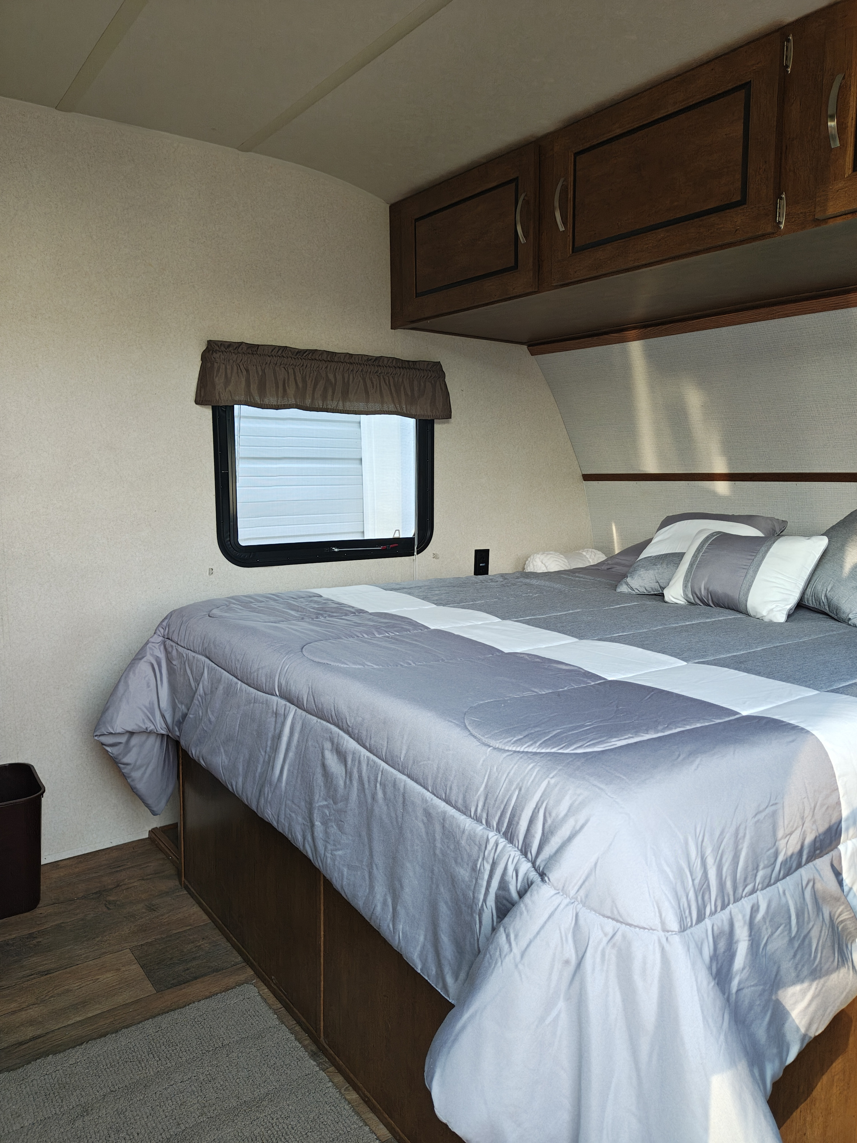 Cozy RV rental bedroom with gray and white bedding, overhead cabinets, and a window for comfortable travel.. Forest River Salem FSX 2018
