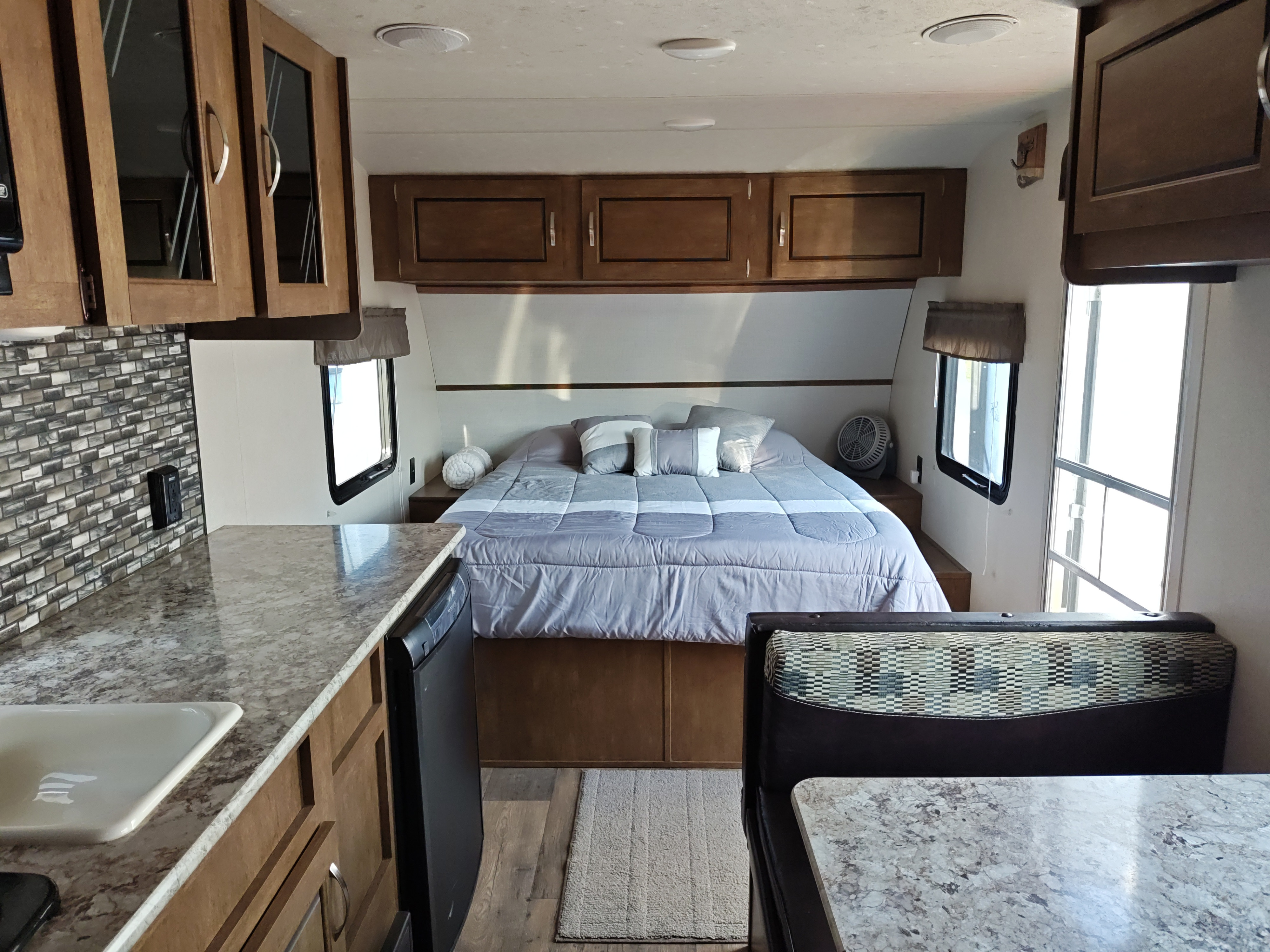 Inside this comfy RV rental: a neat bedroom, well-equipped kitchen with counter & sink, plus a dining booth.. Forest River Salem FSX 2018