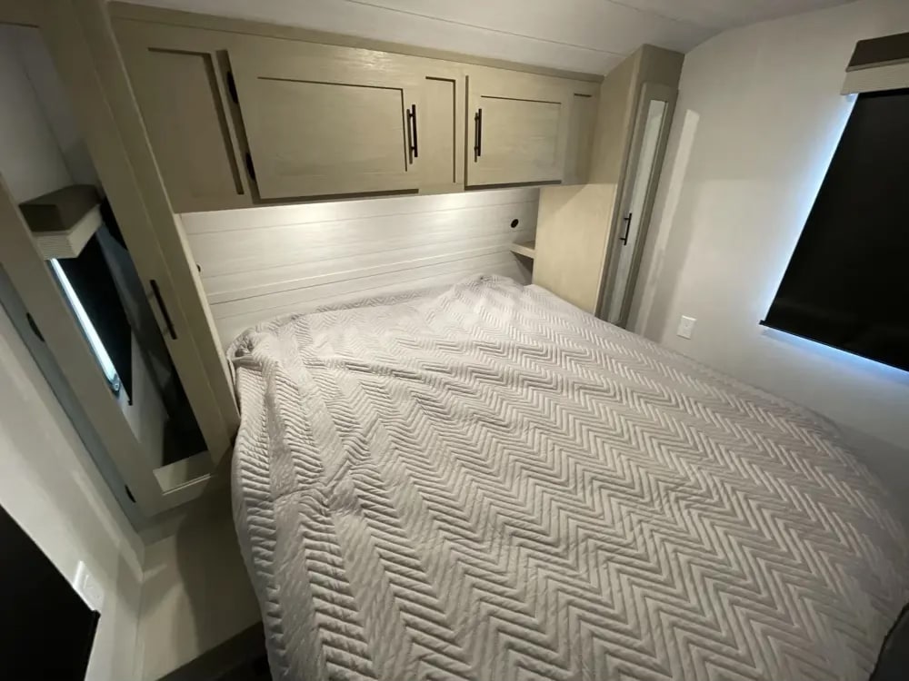 RV rental bedroom: grey chevron bed, overhead cabinets for storage, and integrated lighting for a compact space.. Forest River Salem Platinum 2024