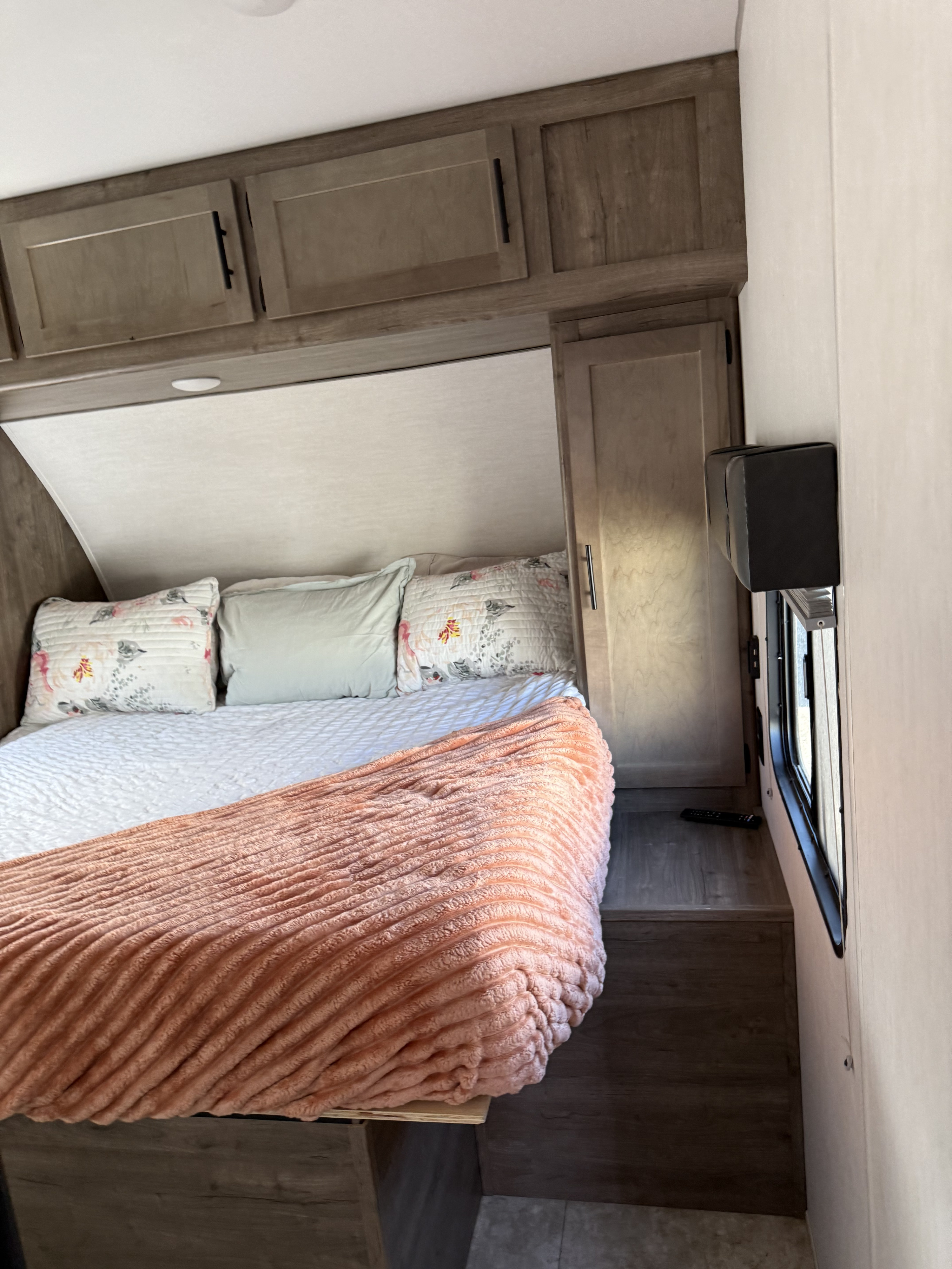 Cozy RV rental bedroom featuring a comfortable bed with fluffy blankets, overhead cabinets, and a window for natural light.. Forest River Vengeance 2022