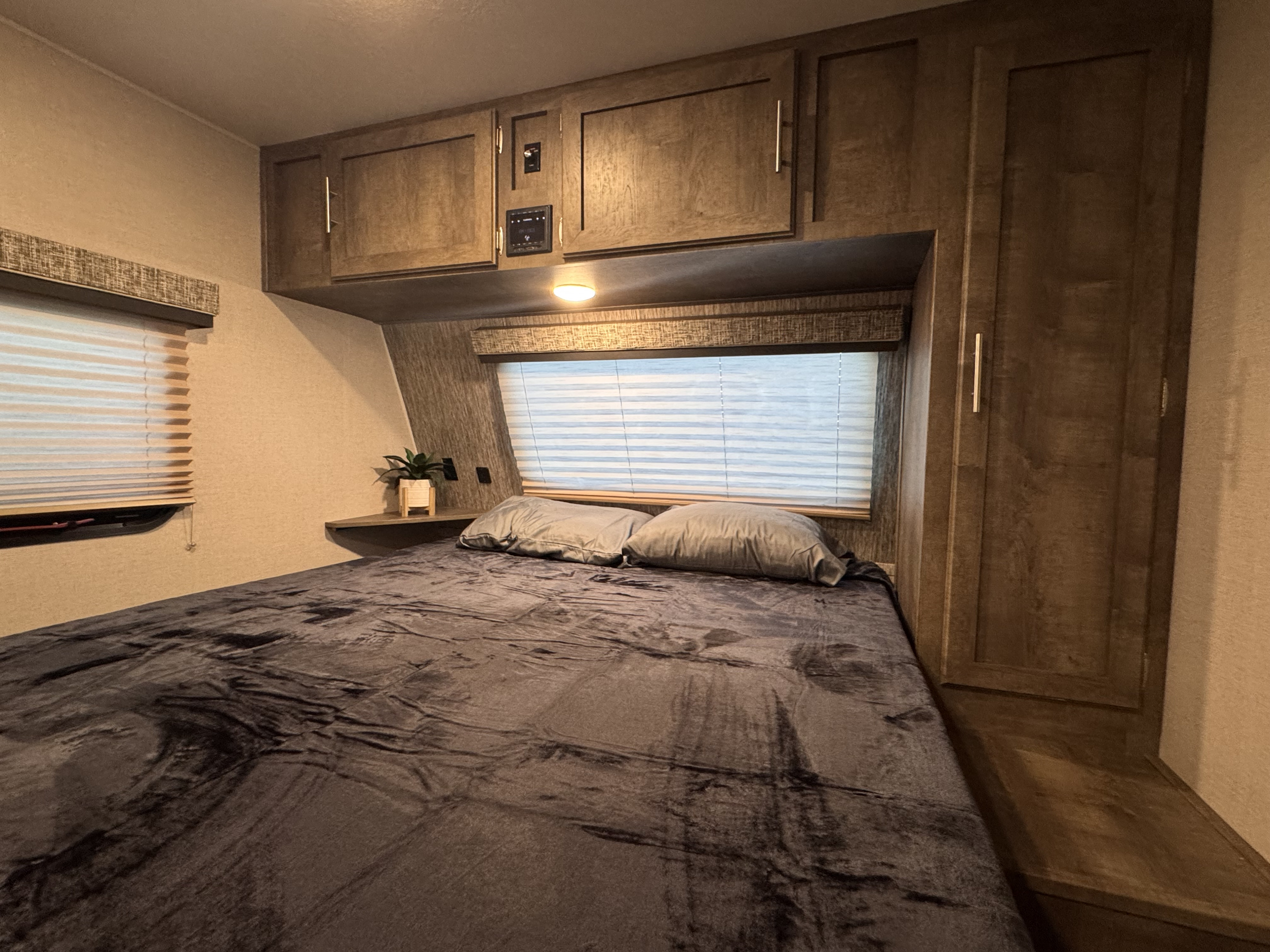 This inviting RV rental bedroom features a plush bed, ample overhead storage, and window blinds, ensuring a restful journey.. Cruiser RV Embrace 2021