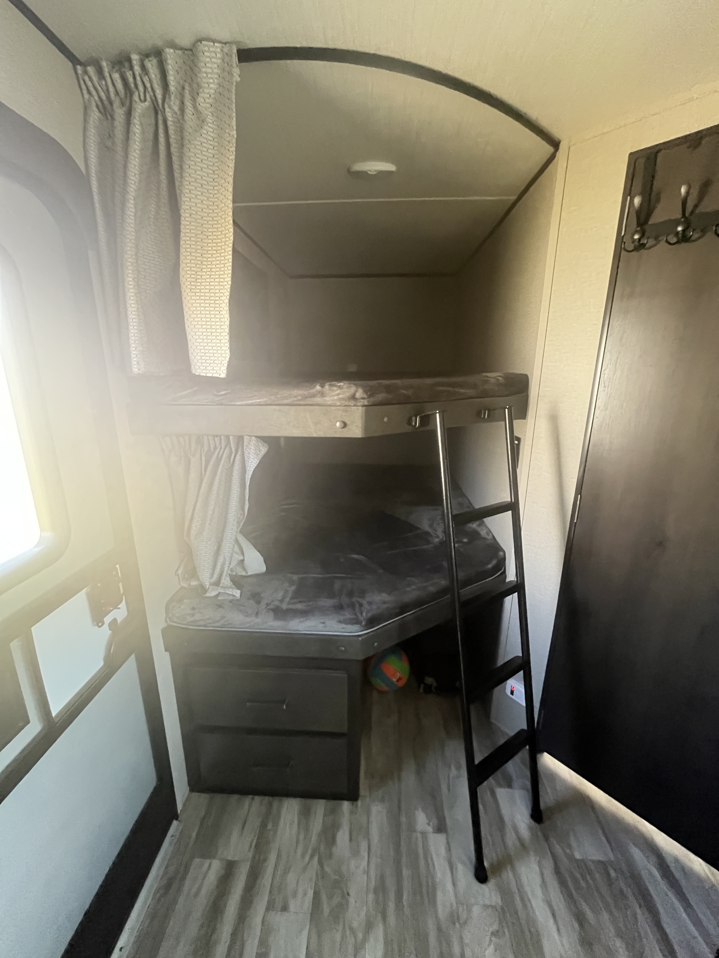 Cozy RV rental bunk beds with ladder, curtains, and storage drawers for a family-friendly sleeping space.. Grand Design Transcend 2020