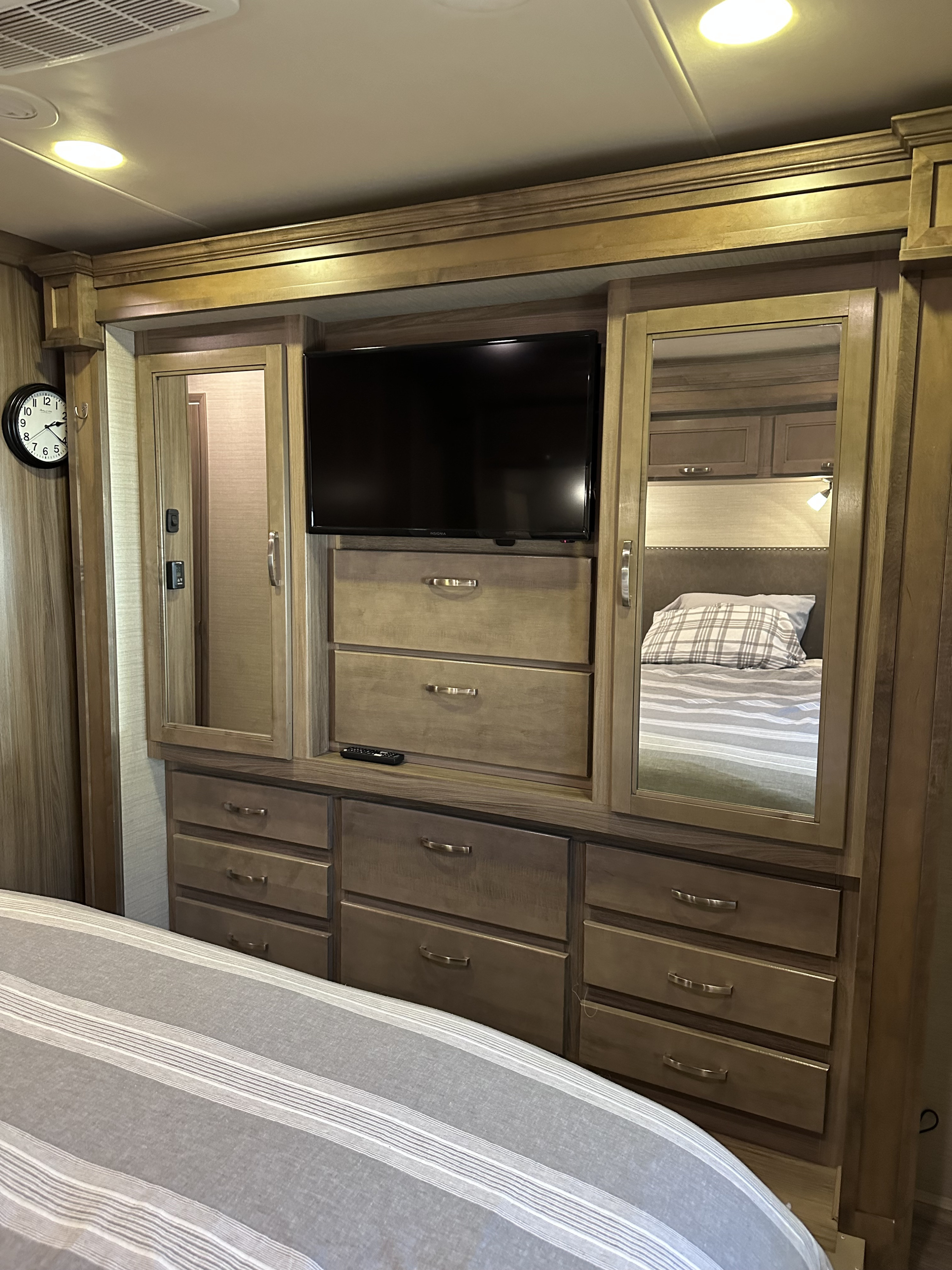 RV rental bedroom with built-in TV, mirrored cabinets, and ample dresser storage. Comfortable striped bedding is visible.. Jayco Precept 2018
