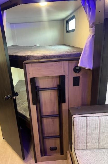 Discover this rv rental's cozy bunk bed, complete with a foldable access ladder and adjacent cushioned seating.. Cherokee Grey Wolf 2025