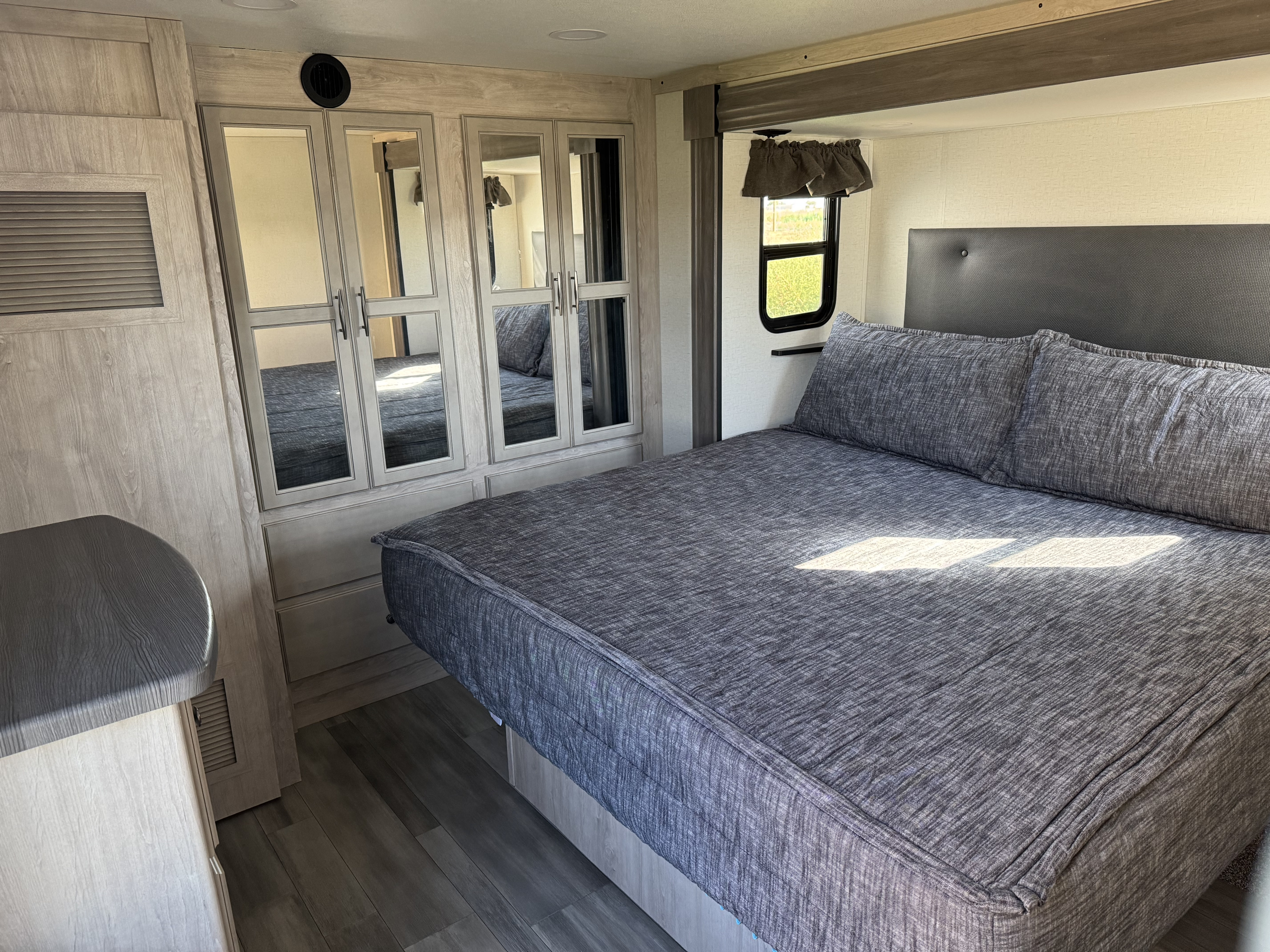 RV rental bedroom with a comfy bed, mirrored closet, headboard, and wood-grain interior. Ready for your travels.. Forest River 4X4FSAS26RJ046944 2024