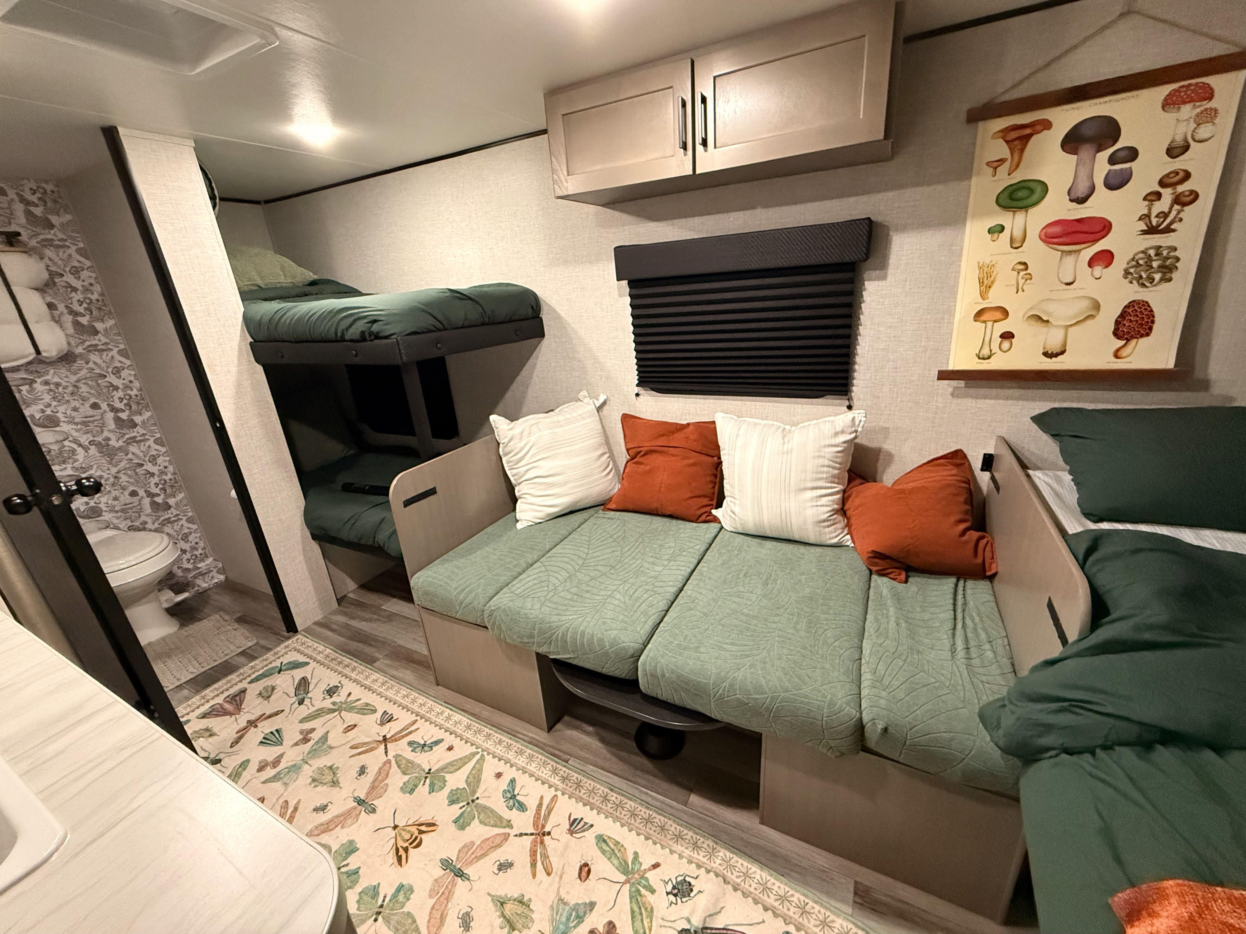 RV rental interior: bunk beds, cozy dinette, and bathroom. Earthy decor with a mushroom chart & bug rug offer a unique camping vibe.. Jayco Jay Feather 17BHSL 2025