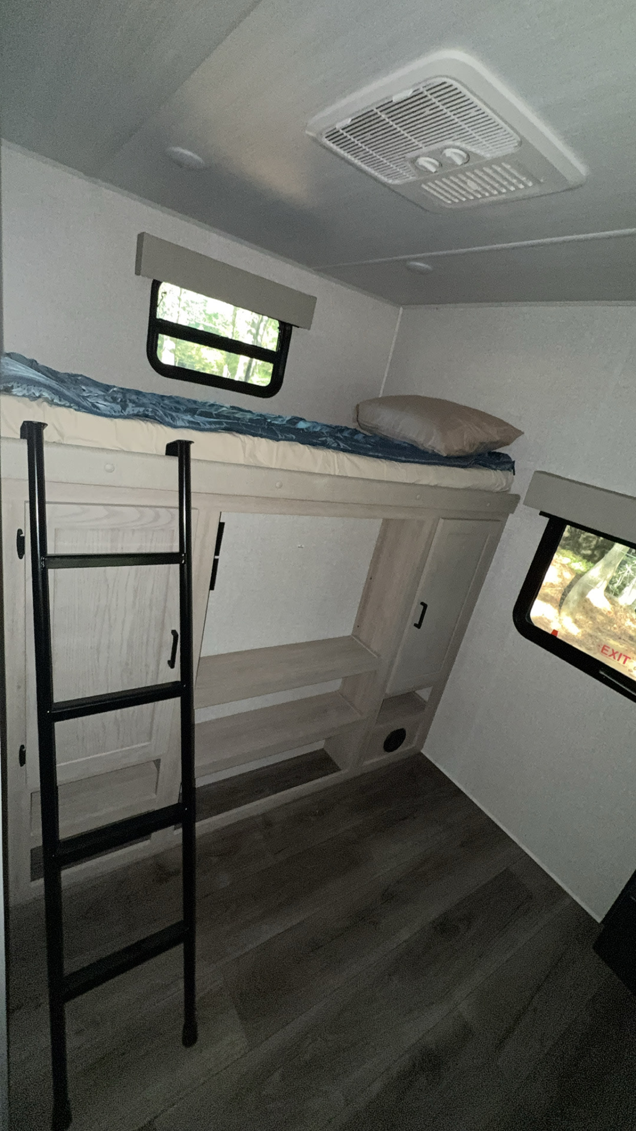 Spacious bunk bed sleeping area in an rv rental, featuring a ladder, windows, and an overhead AC unit for comfort.. East to West Alta 2023