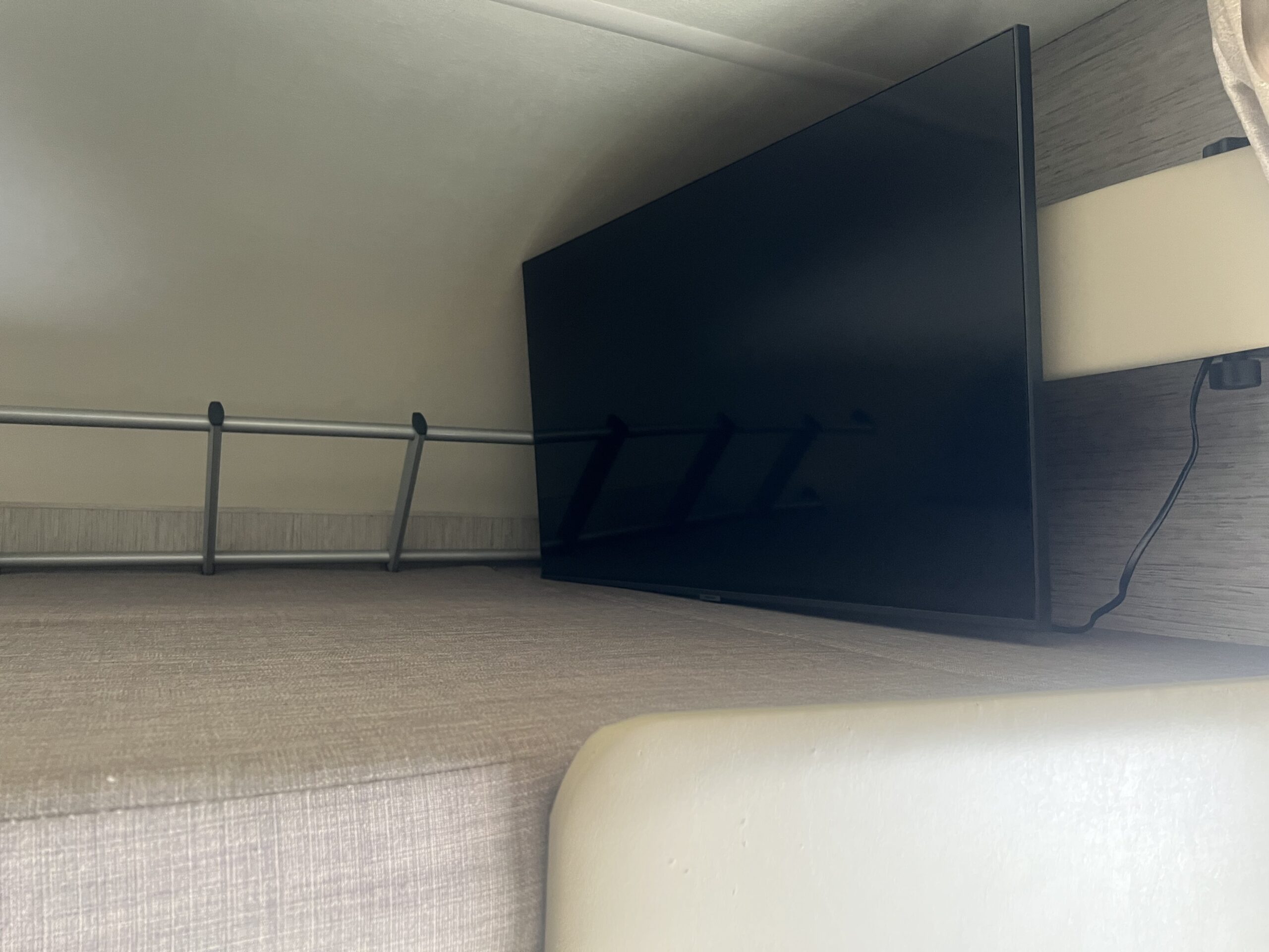 Compact RV rental interior featuring a TV, a bunk bed with a safety rail, and a light-colored cushion.. Thor Freedom Elite 2021