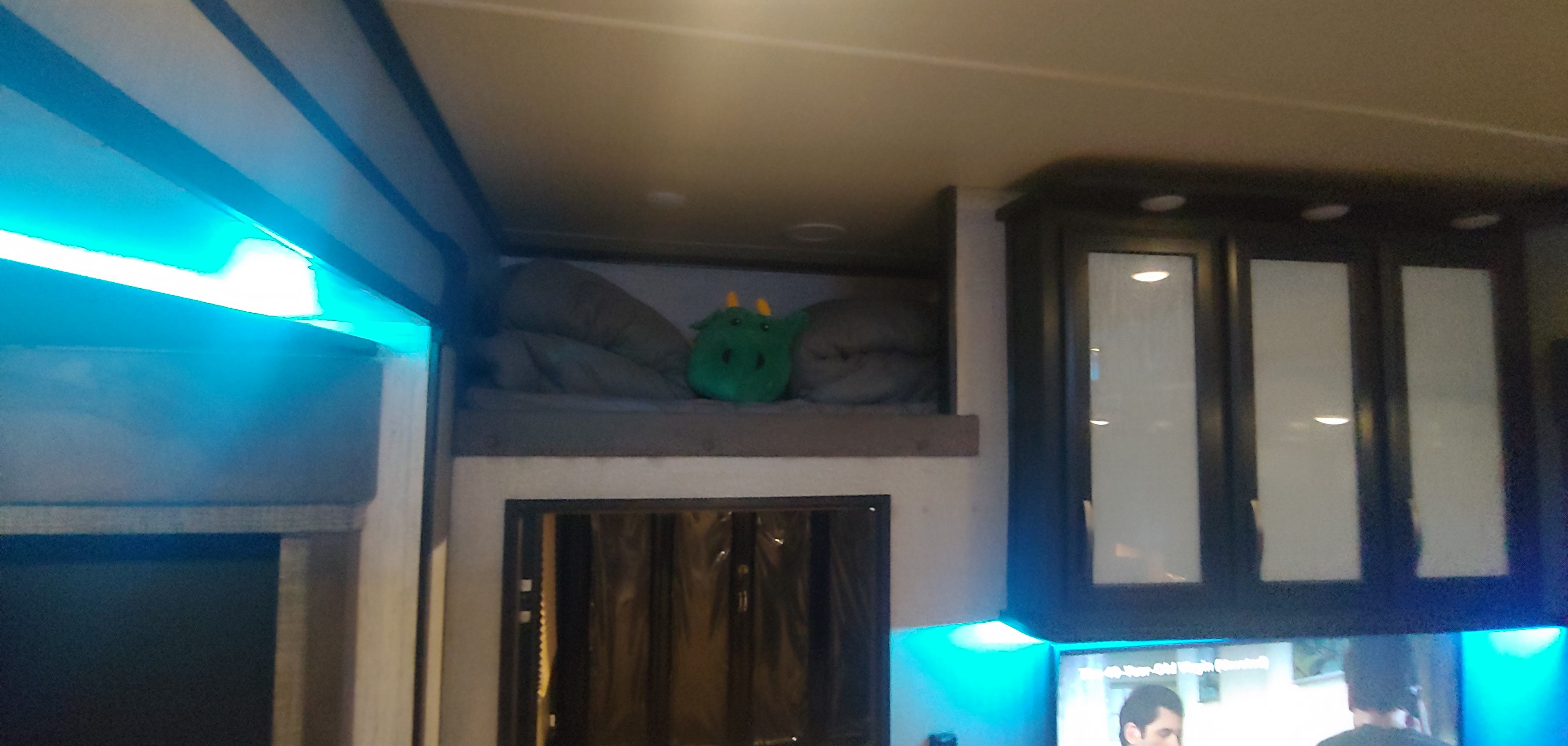Cozy RV rental interior features a bunk bed with a dragon plush, blue LED lighting, and modern cabinets.. Grand Design Momentum 2018